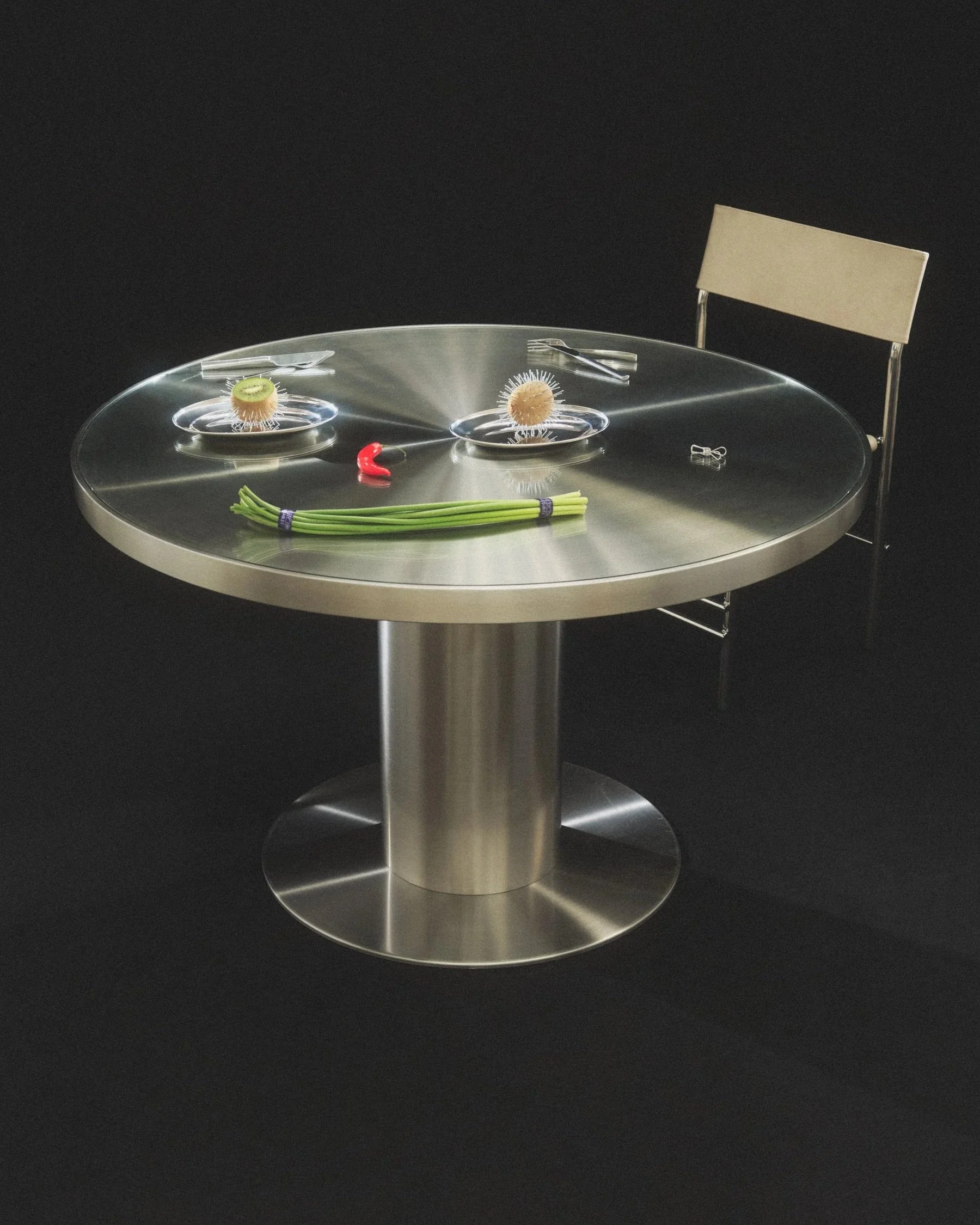 A still life photo of a silver table with a cartoon face. The face is created from food and silver dinnerware.