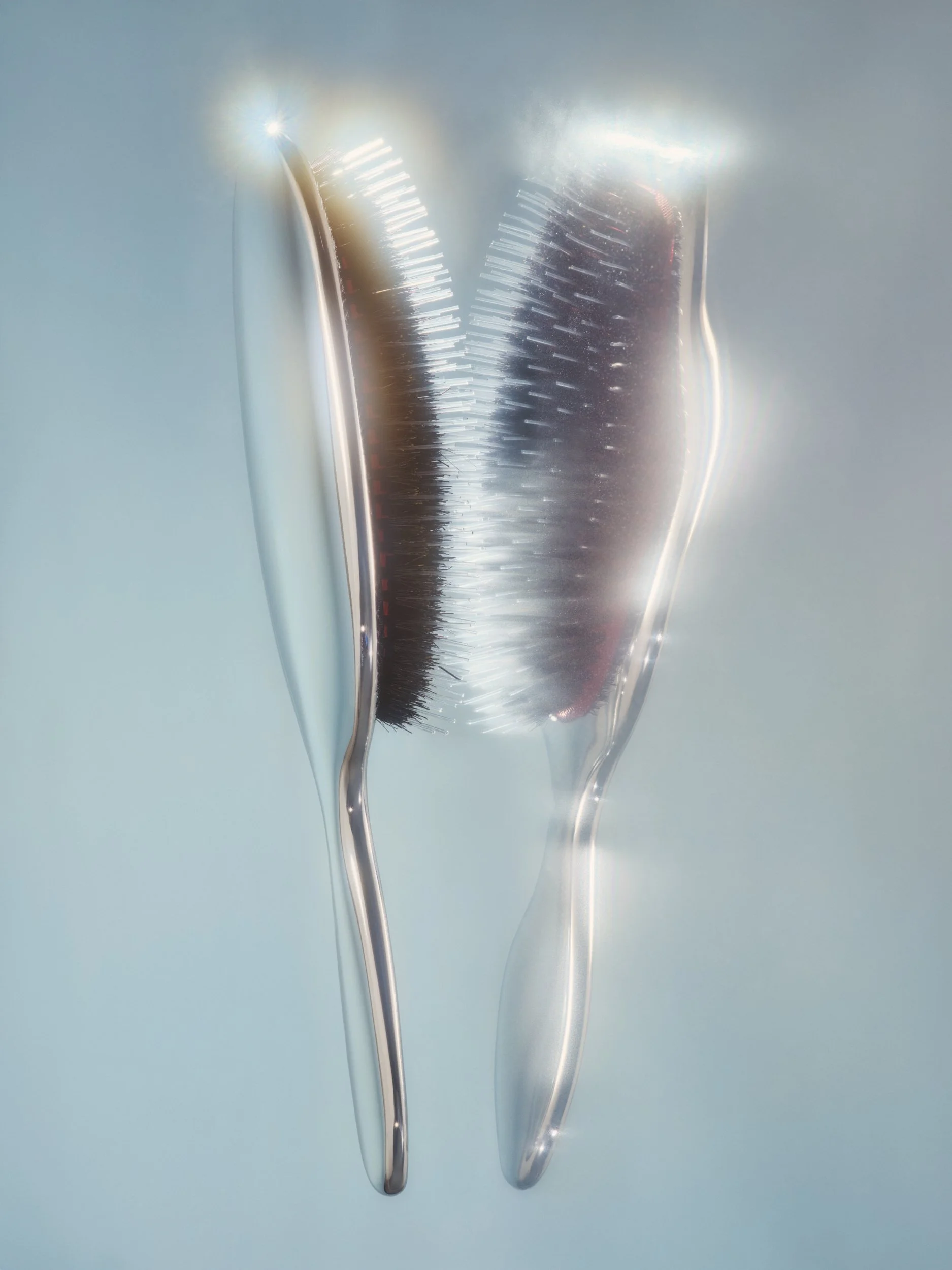 Photo of a sliver hair brush and its reflection glowing with light.