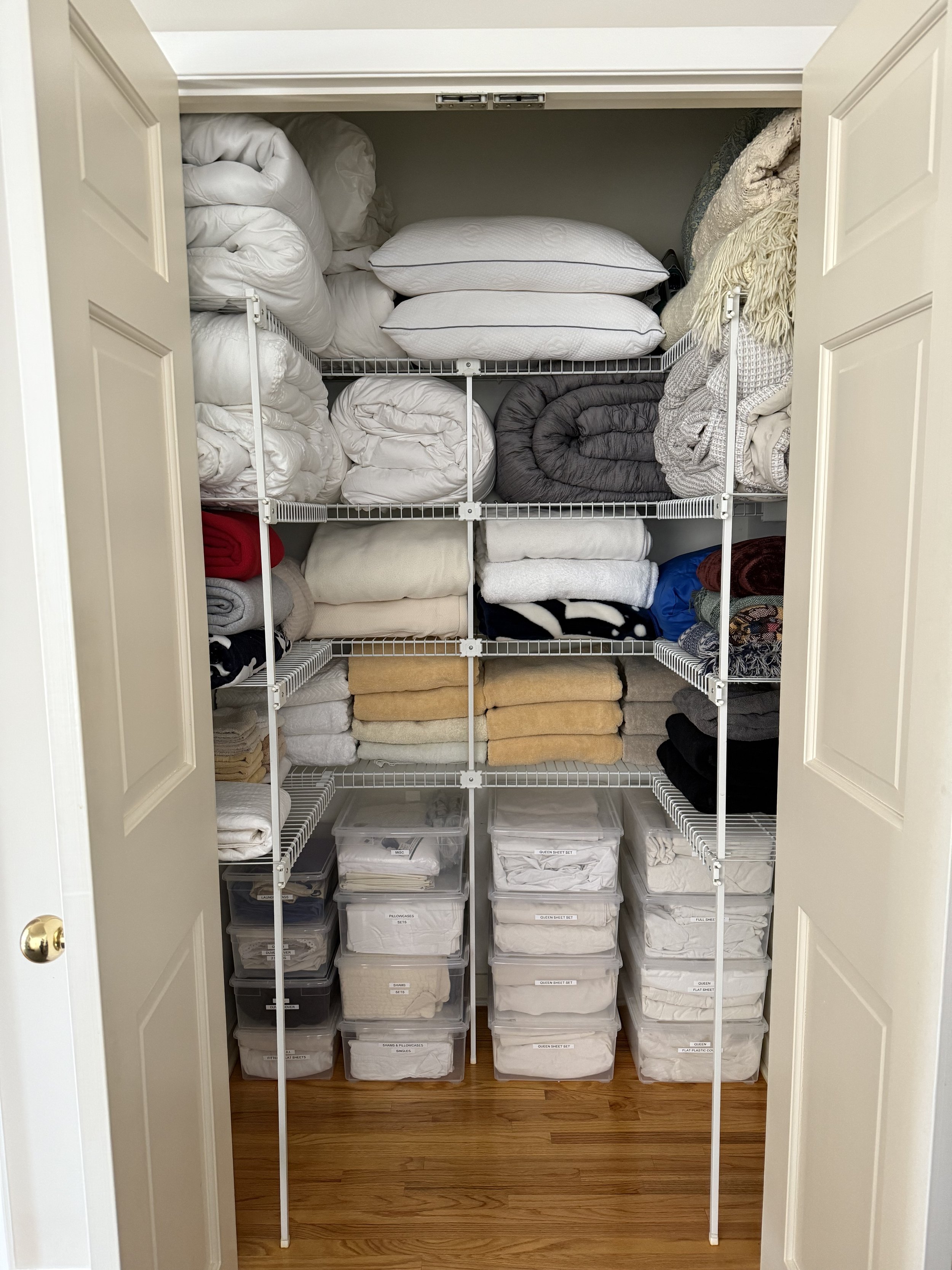 Organized linen closet after professional organizing in Mercer County, Central New Jersey, with folded bedding and labeled storage bins.