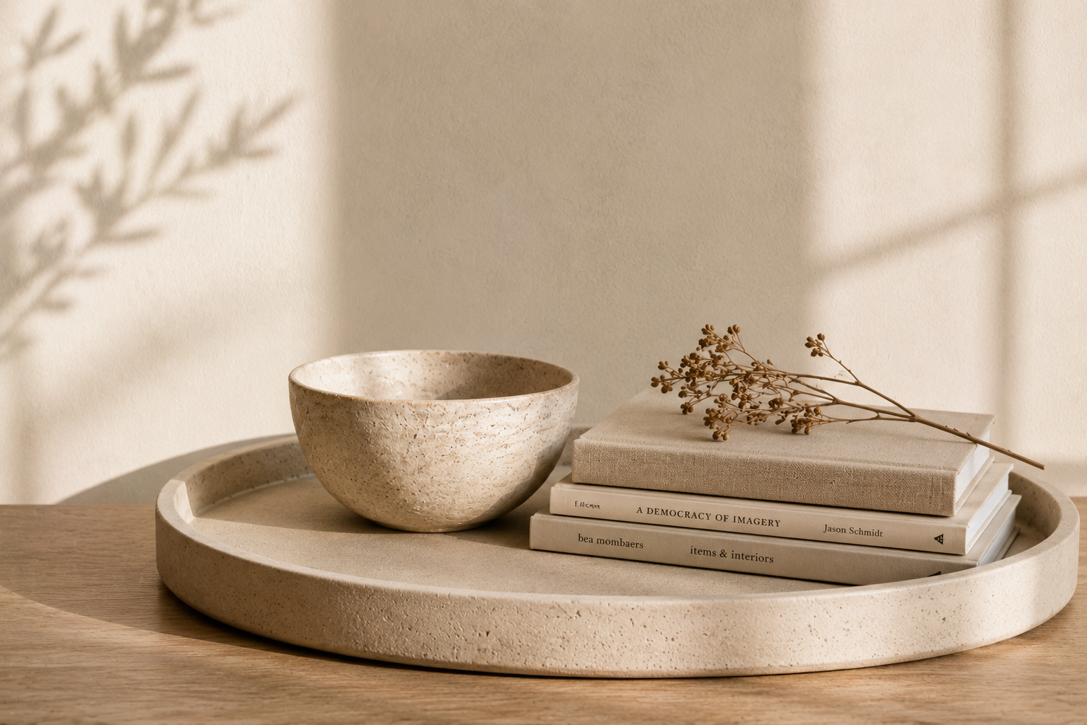 Neutral ceramic bowl and stacked linen books on a stone tray with dried botanicals and soft natural light.