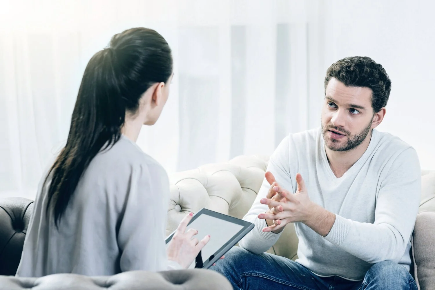 Man sitting in a therapy session, appearing deep in thought and processing difficult emotions.