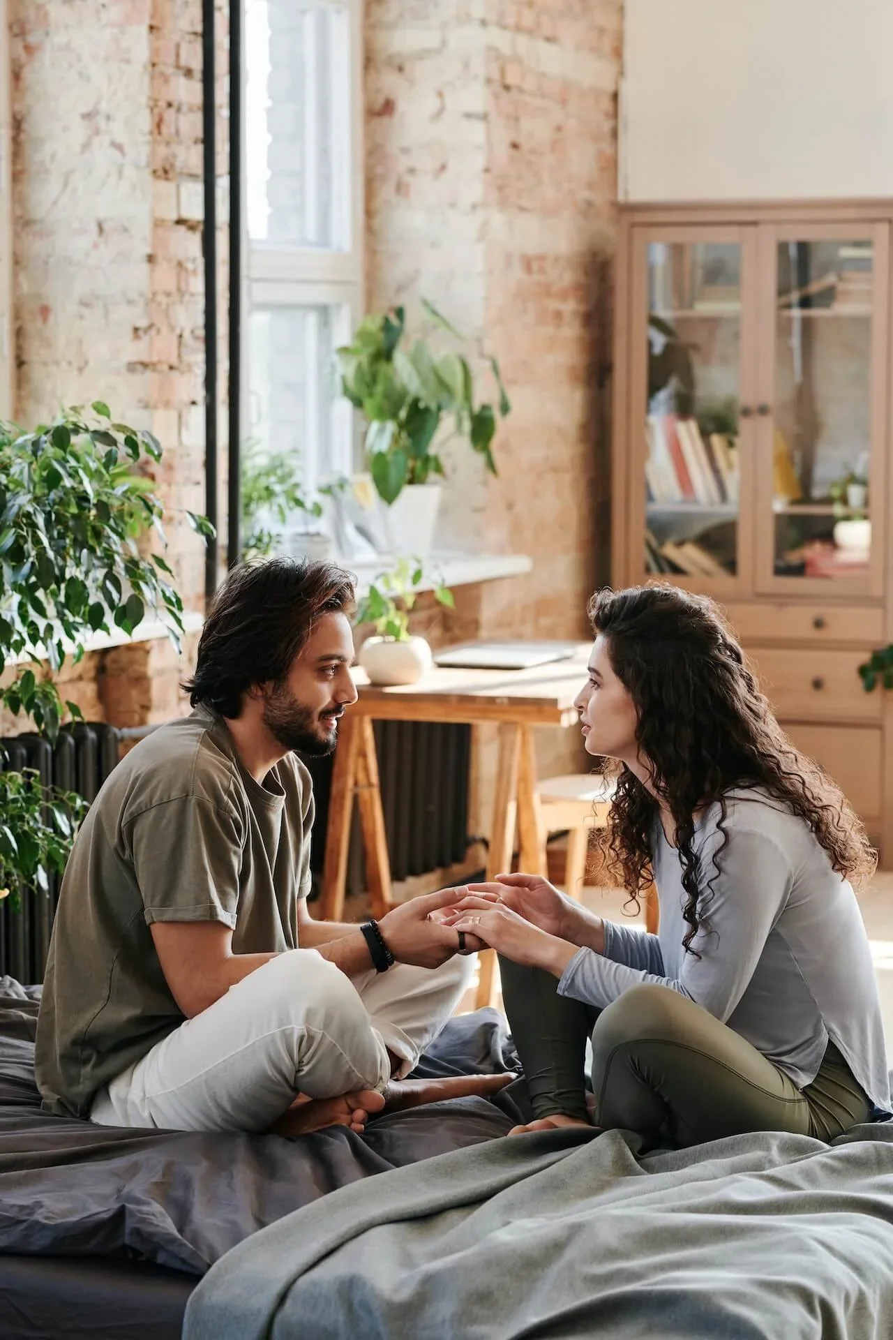 Couple sitting close together and holding hands while talking in a warm, cozy living room, reflecting connection, communication, and emotional support
