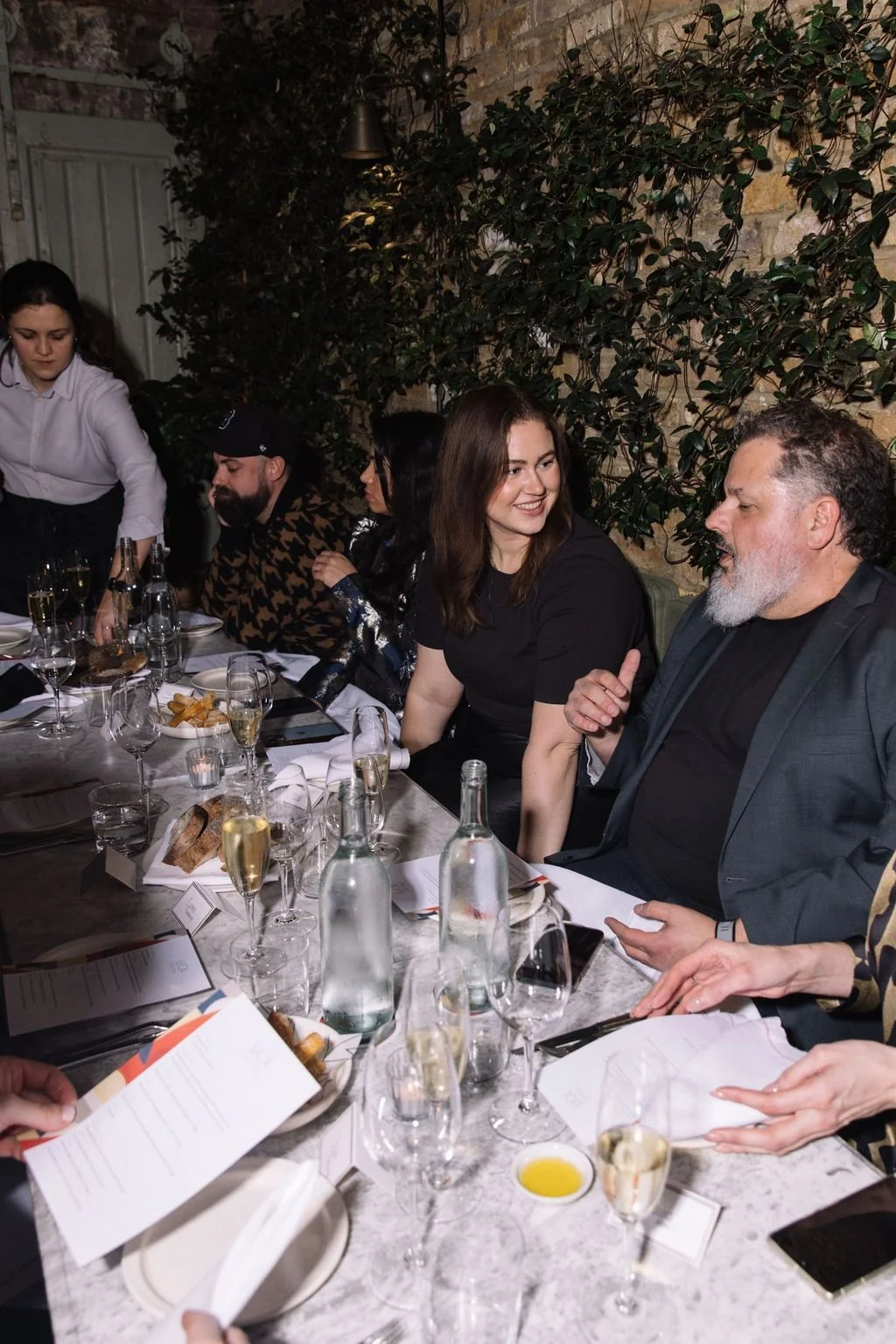 People gathered at a dinner table with drinks and food.