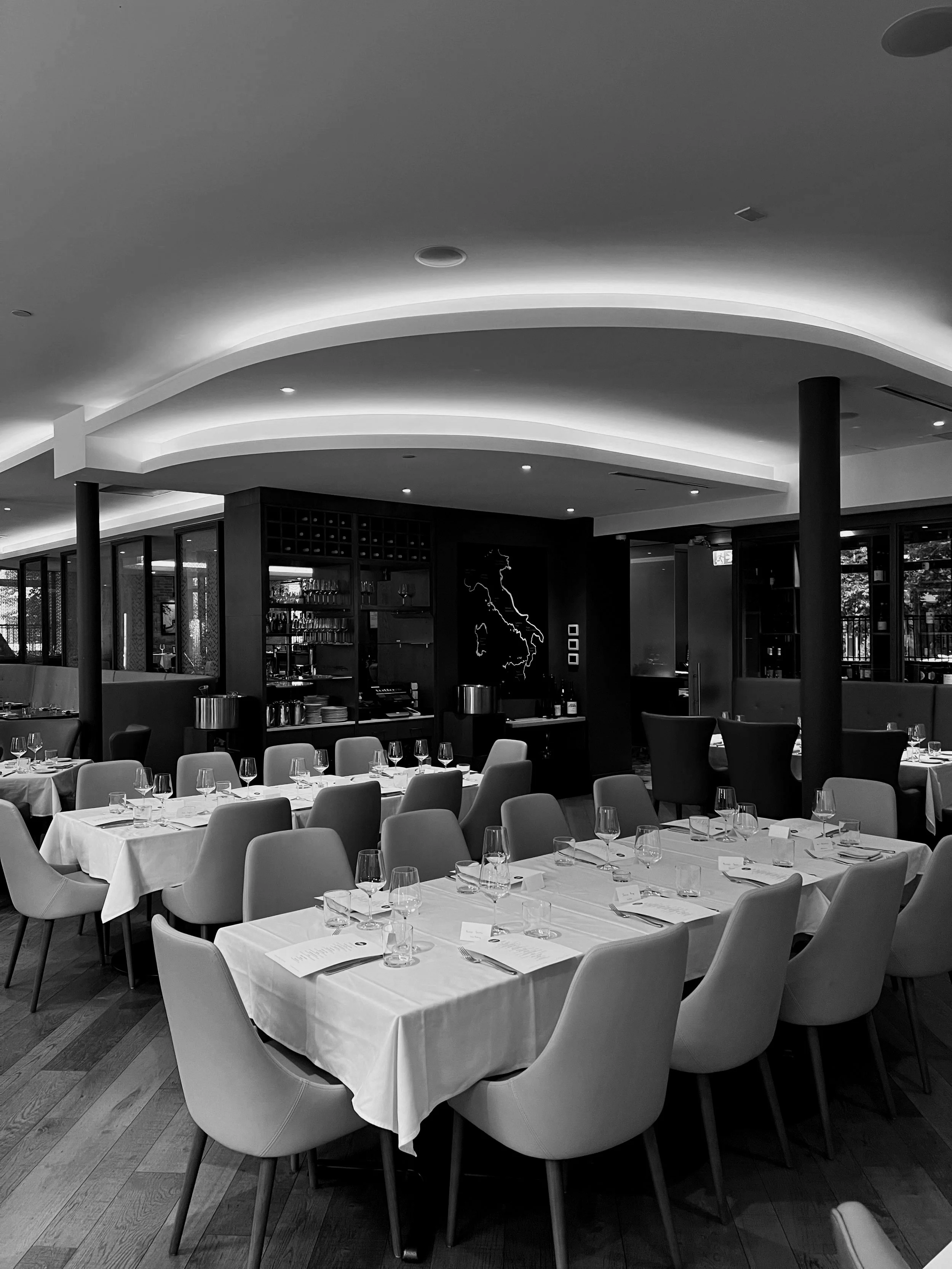 Elegant restaurant interior with neatly arranged tables and chairs, ambient lighting, and modern decor in black and white.