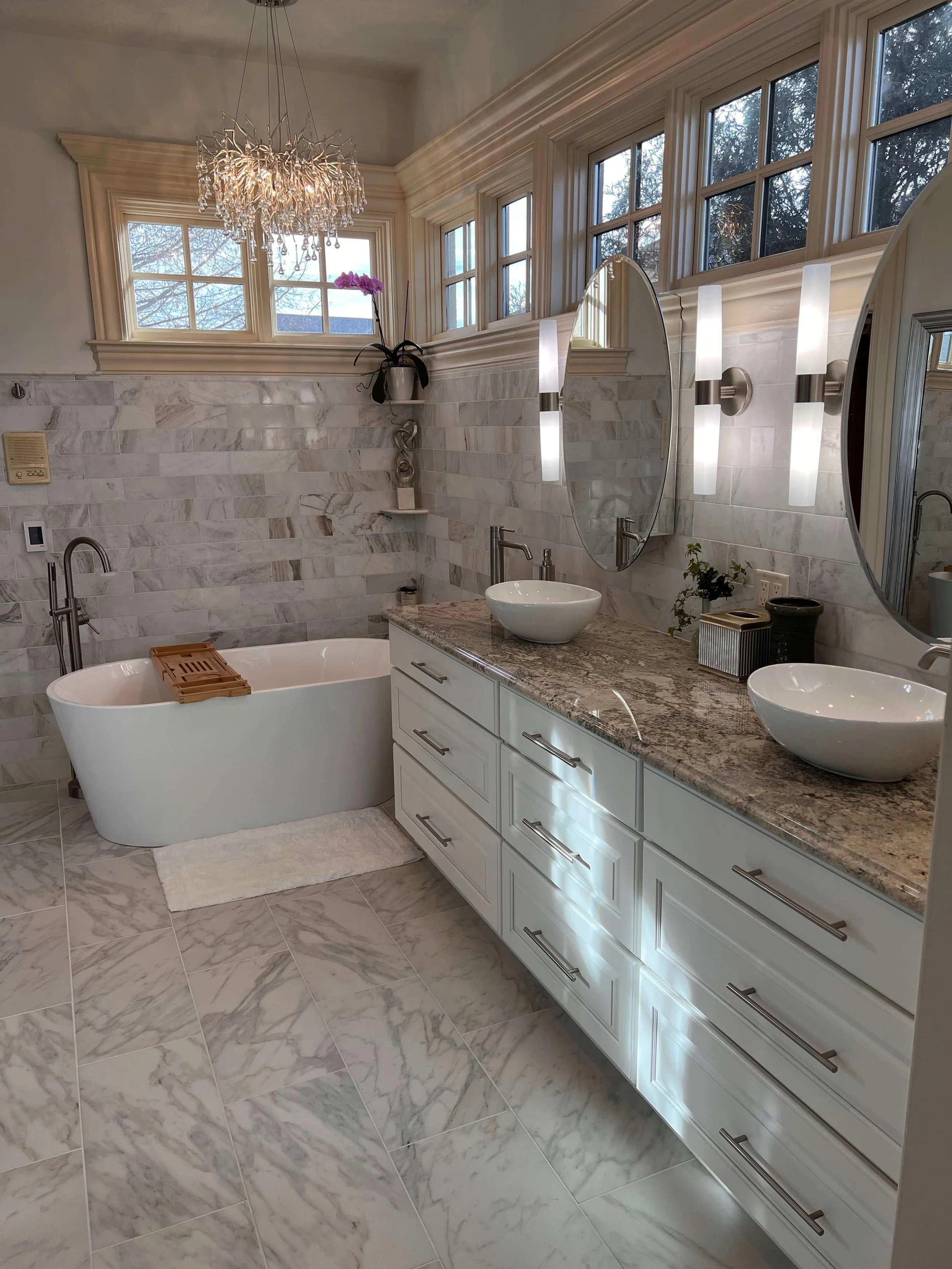 Contemporary bathroom vanity update with floating wood cabinets, dual sinks, and updated LED mirror lighting.