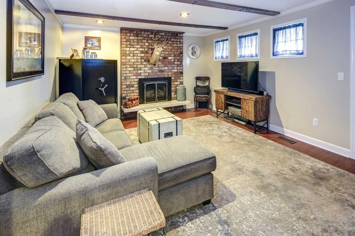 Spacious Des Moines finished basement with white sectional, wood-look LVP flooring, and home theater zone.