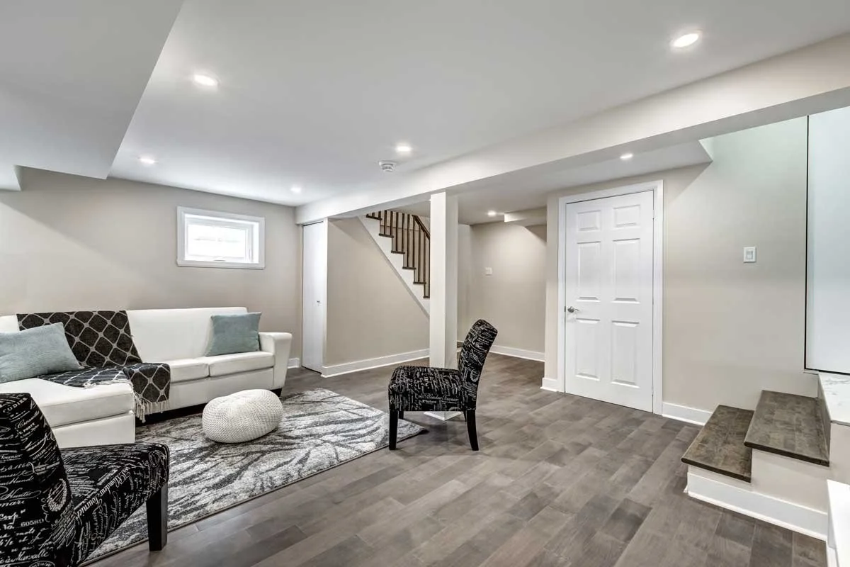 Modern Urbandale basement living room featuring a beige sectional, geometric rug, and recessed lighting.
