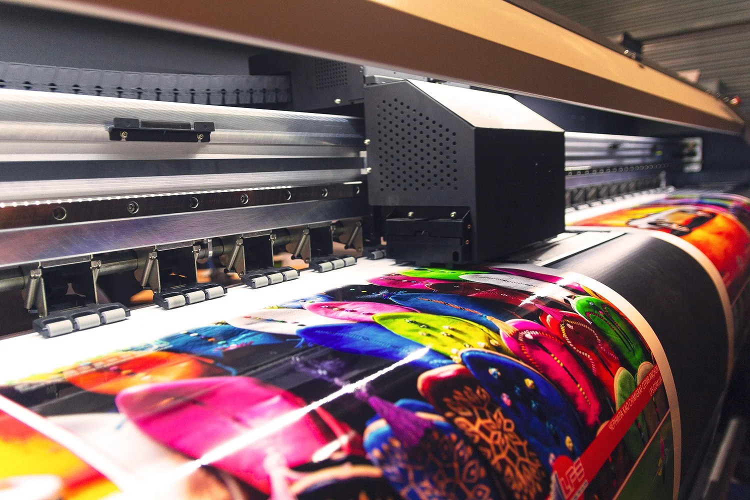 A large printing machine producing a colorful, vibrant poster with abstract patterns.