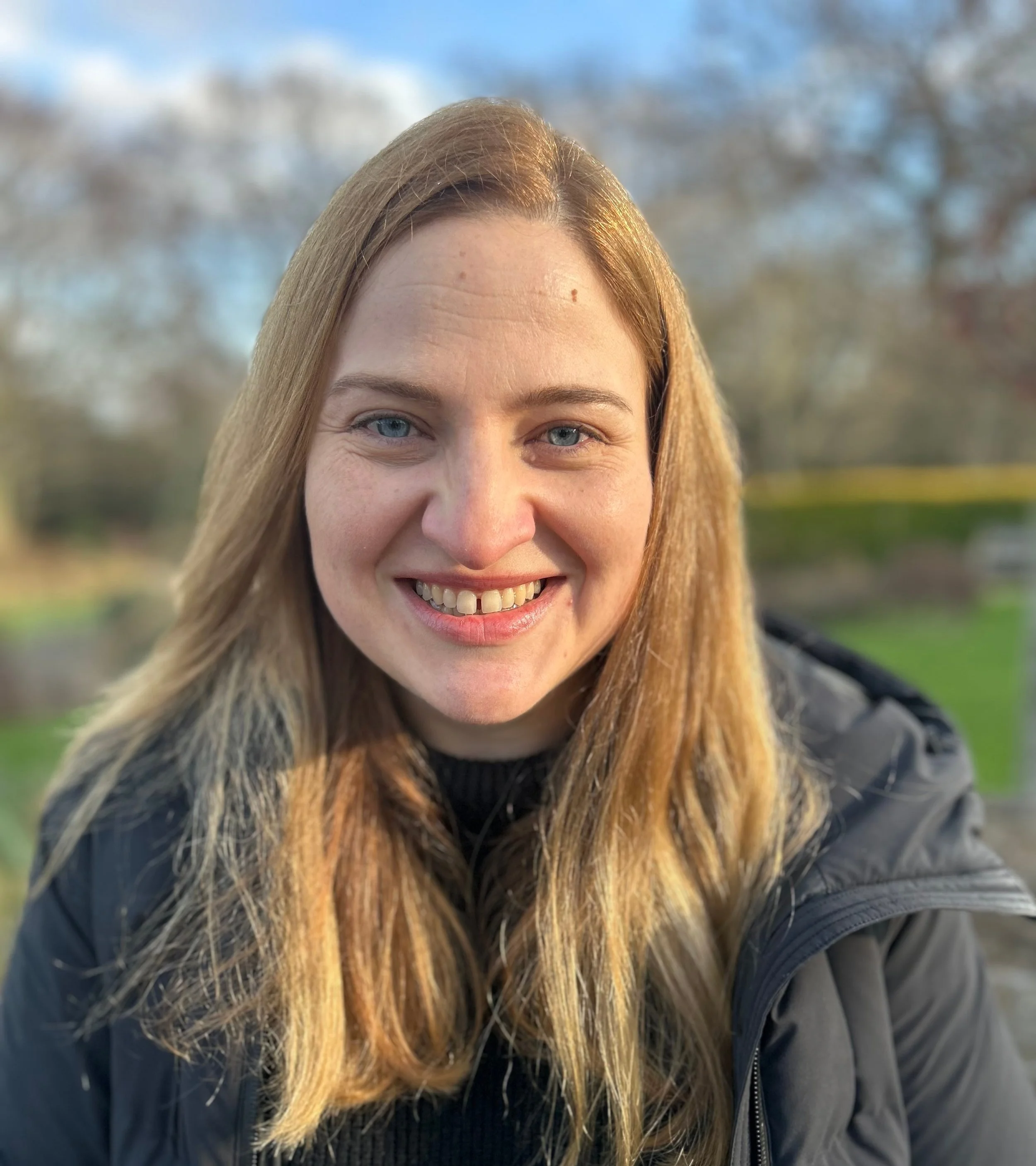 Smiling woman outdoors with trees in the background