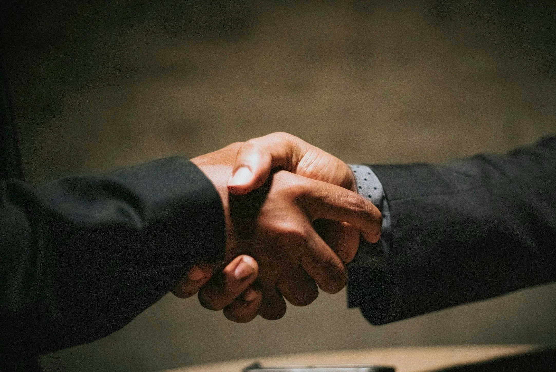 Zwei Personen in Anzügen schütteln sich die Hand.