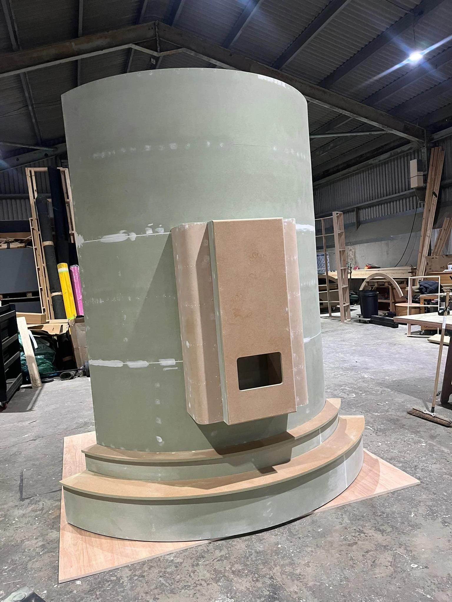 THE BUZZBALLZ gatcha  in a workshop, with steps at the base and a rectangular protrusion on the front, possibly part of a decorative or architectural installation.