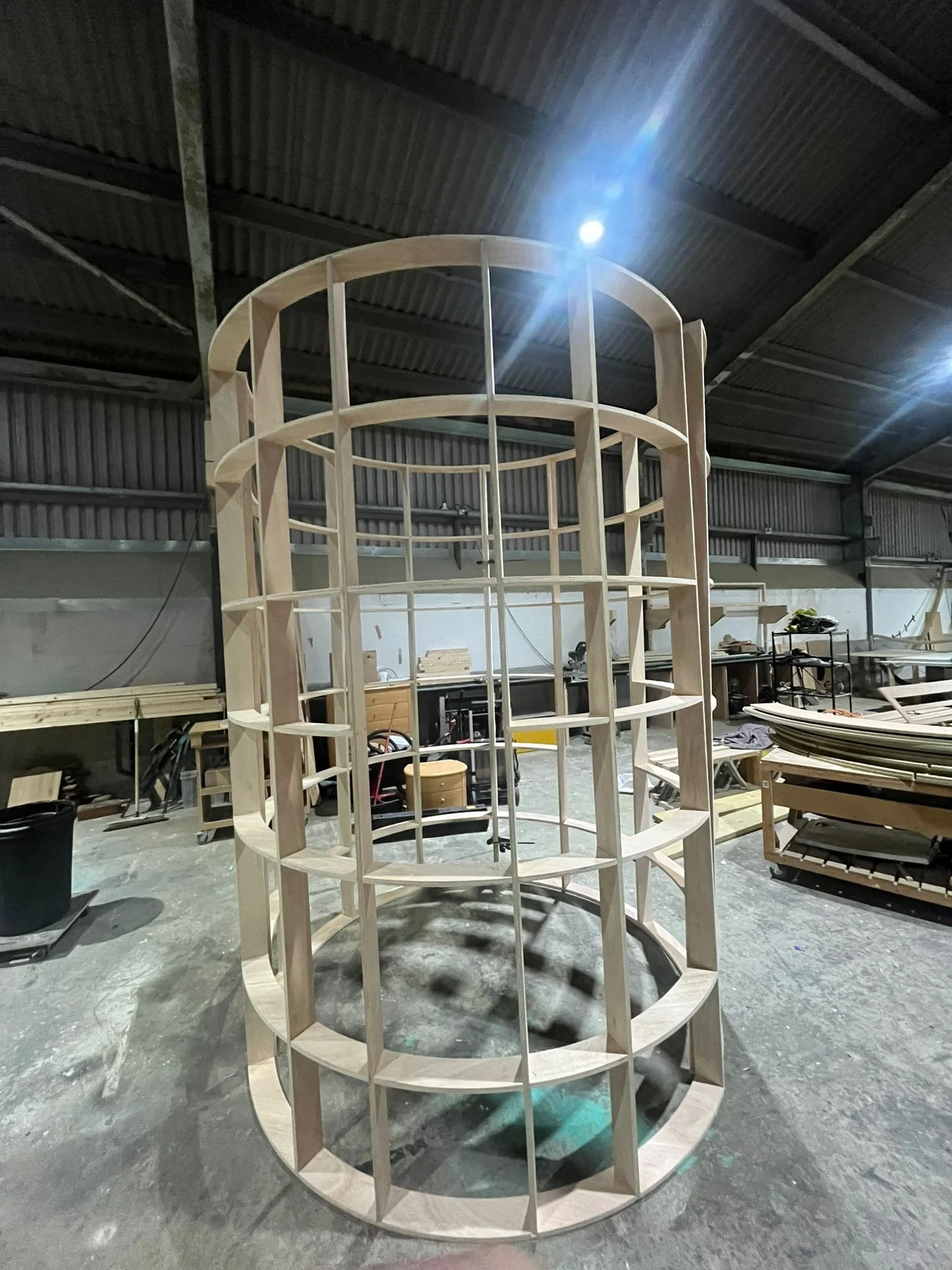 Wooden circular BUZZBALLZ gatcha  in a workshop with various woodworking tools and materials in the background.