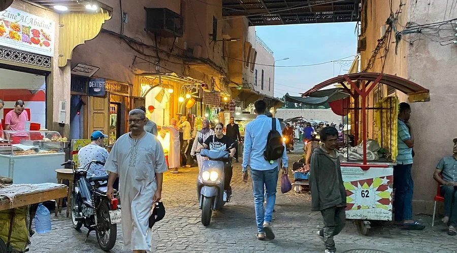 Straatbeeld in een drukke markt met winkels, mensen en een voedselkraam in een oude stad.