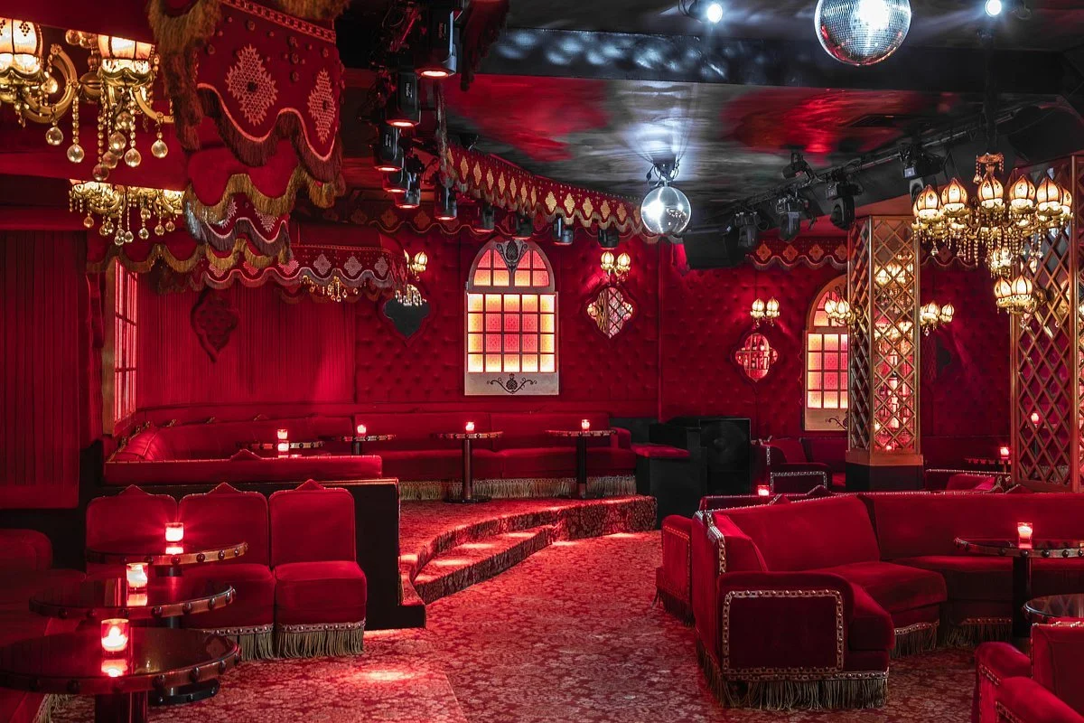 Een luxueuze, rood-gekleurde club met velvet banken, kroonluchters en sfeerverlichting, klaar voor een avond vol entertainment.