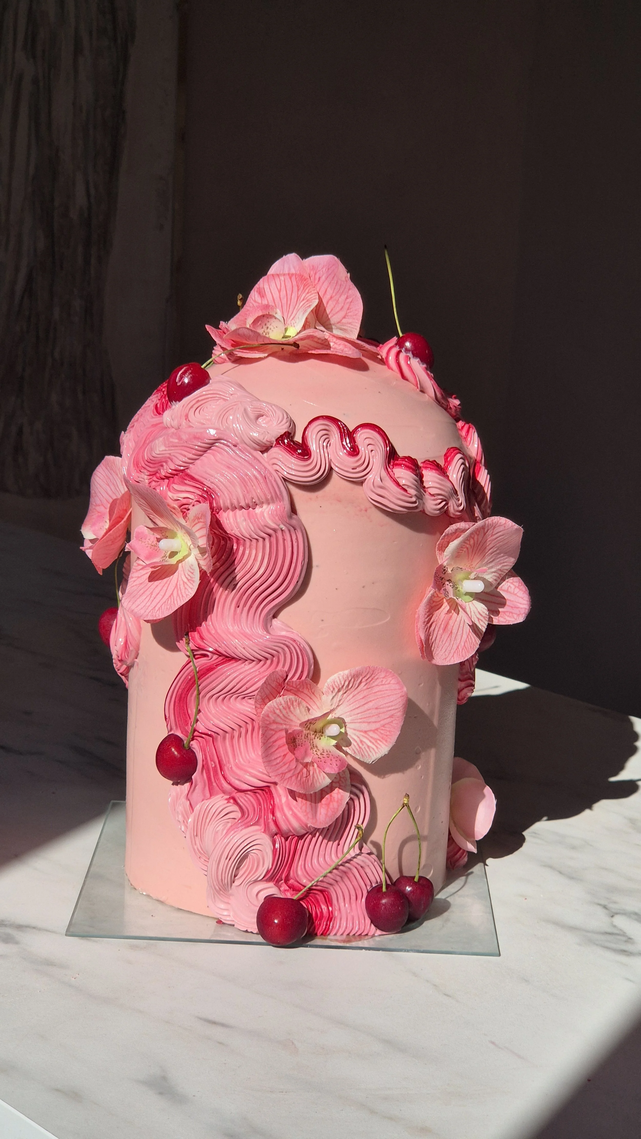 Gateau anniversaire sur mesure, cake design maison TCHOVI .Un gâteau rose décoré de fleurs d'orchidée et de cerises.