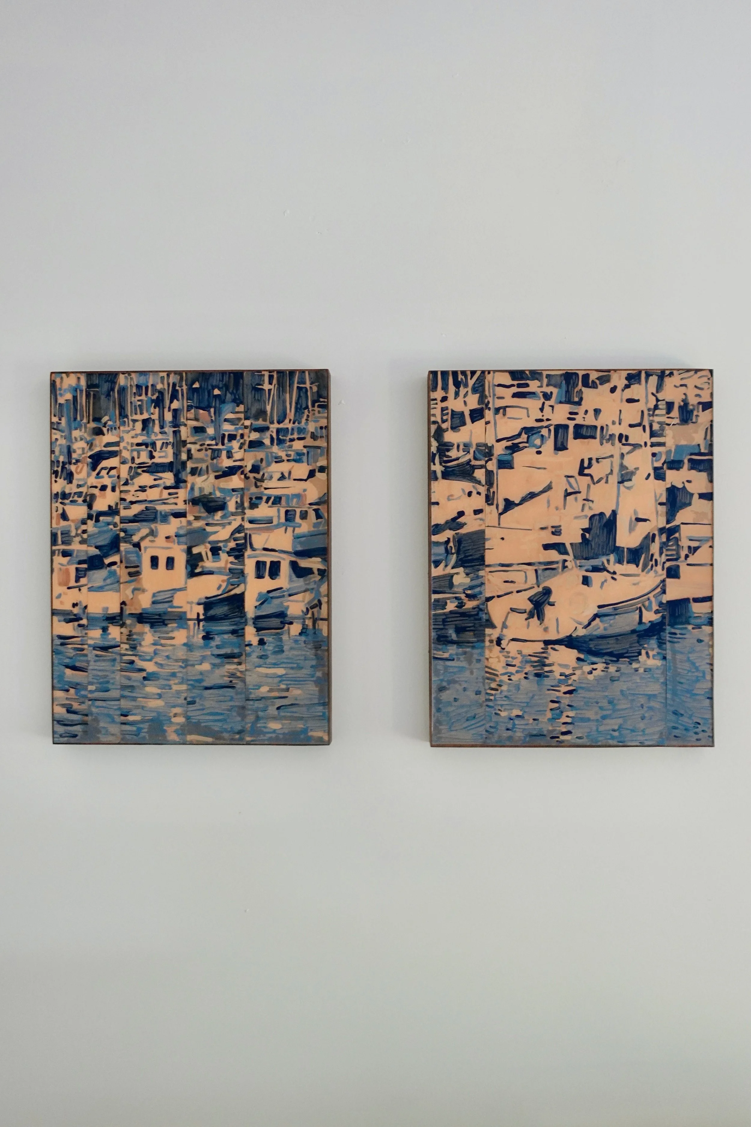 Two rectangular paintings featuring boats on the water and reflections in water, mounted on a white wall.