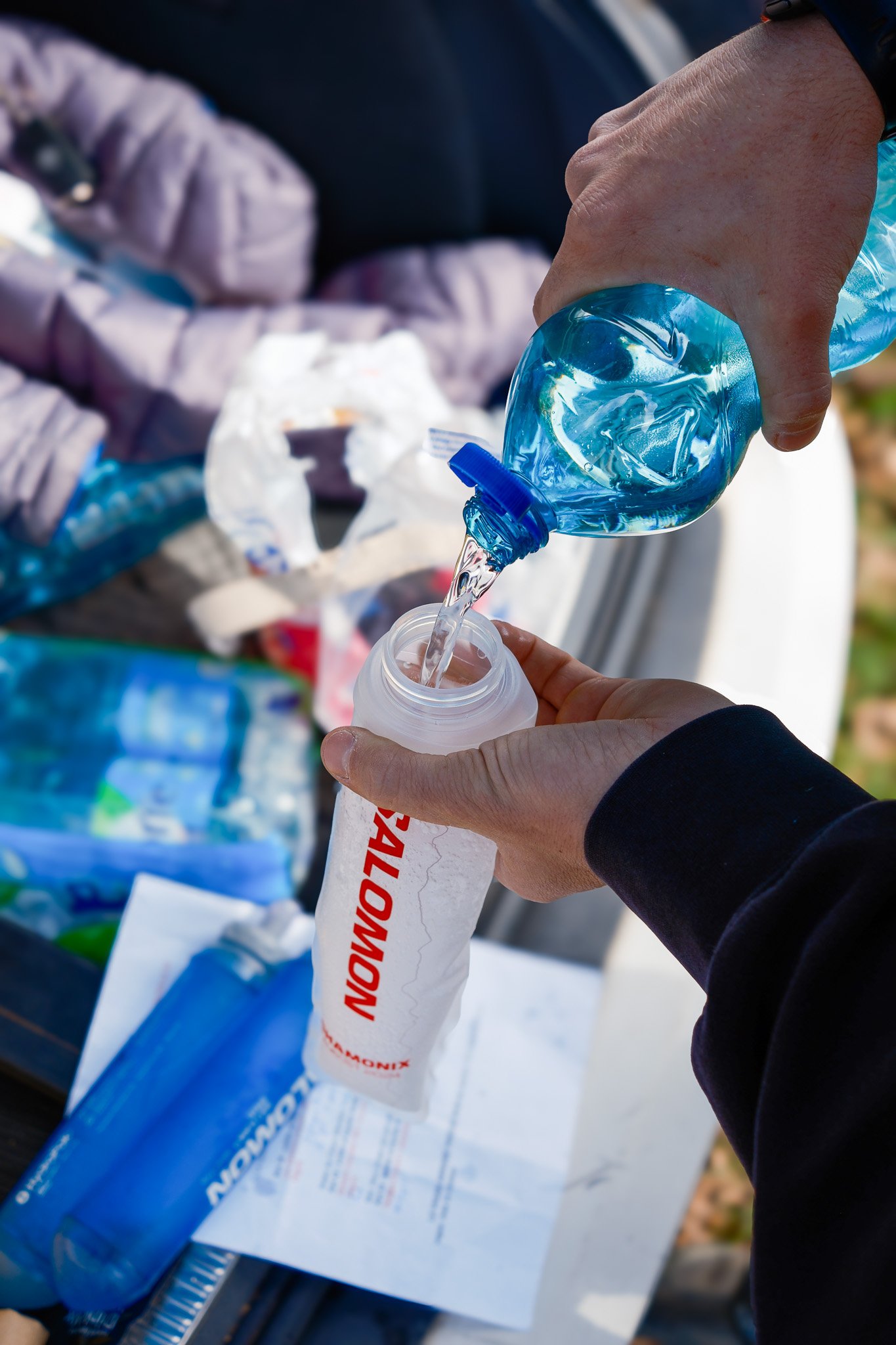 Remplissage d'une bouteille d'eau avec une autre bouteille. Objets épars en arrière-plan.
