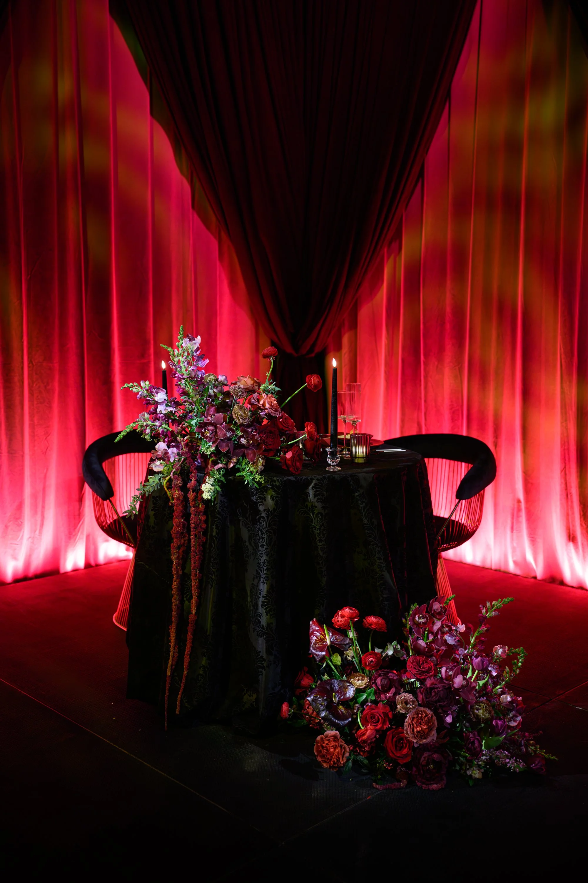Dramatic Wedding Tablescape with Red Drapery and Lush Floral Arrangement