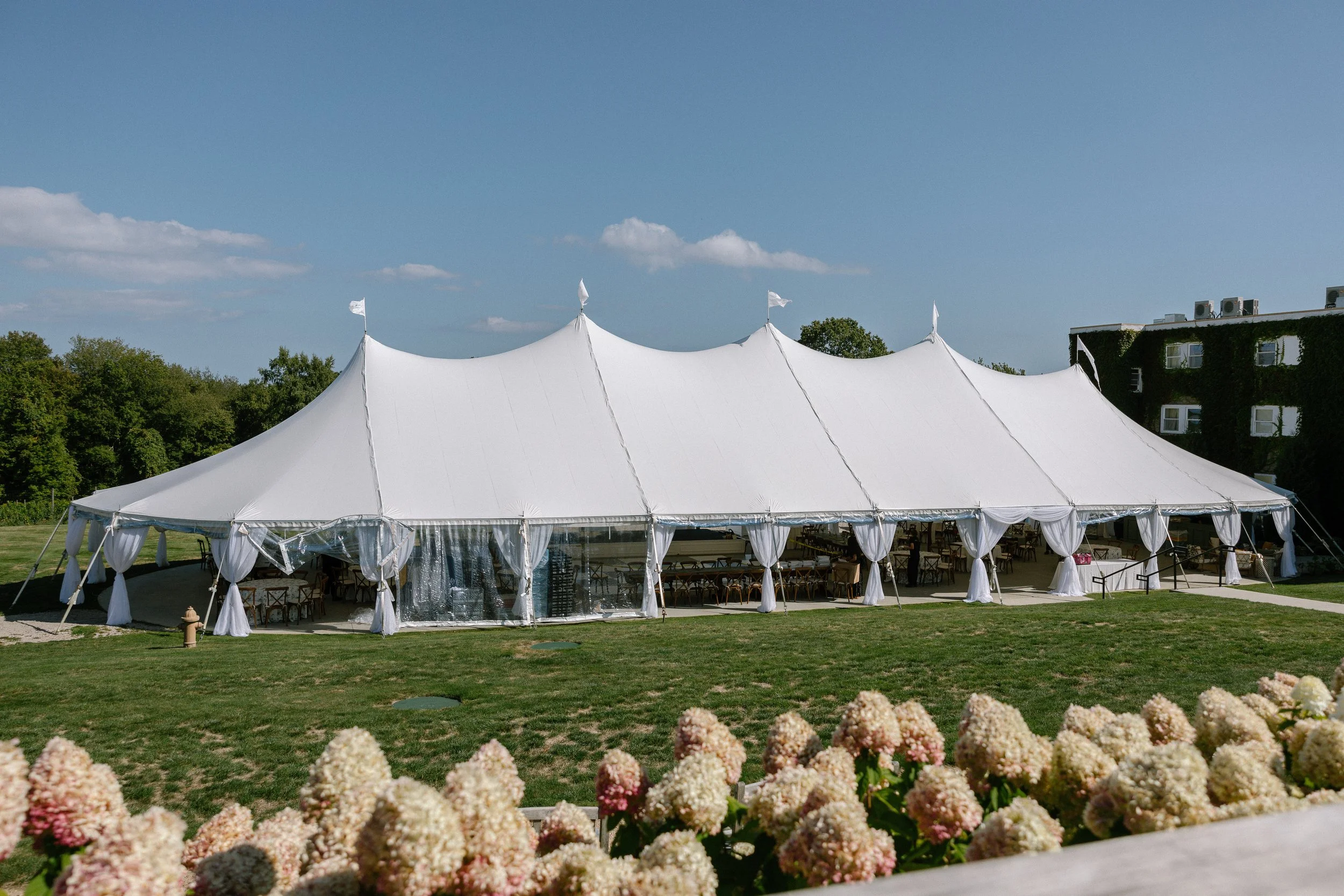 Large luxury sailcloth wedding tent set on a landscaped lawn at a Rhode Island wedding venue, prepared for an elegant outdoor reception with panoramic countryside views
