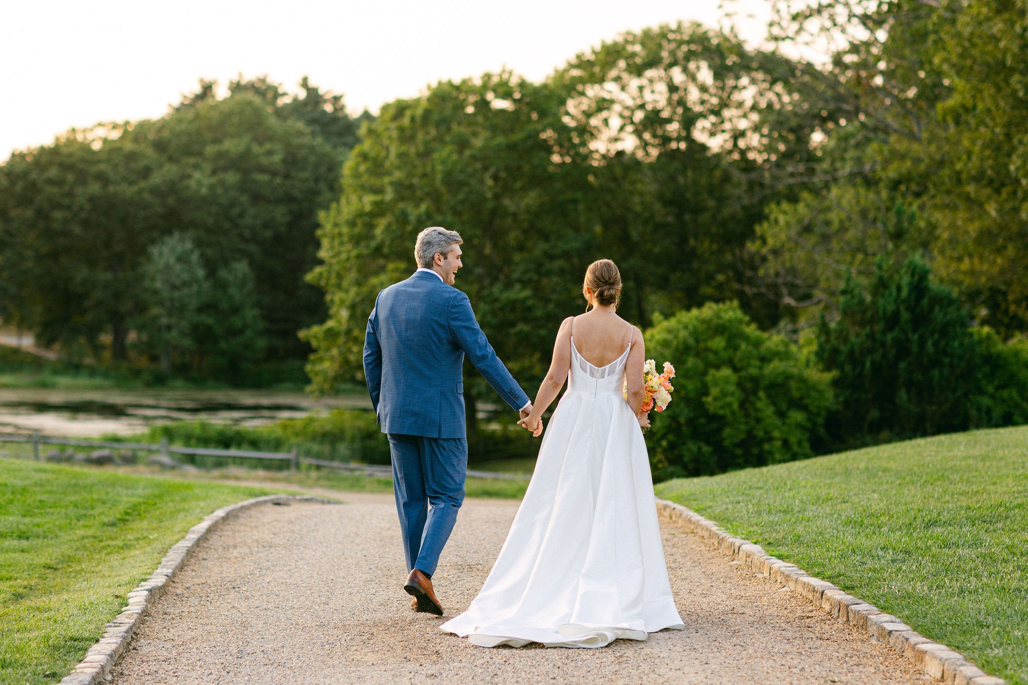 Bride and groom walking hand in hand outdoors at a New Hampshire wedding venue.