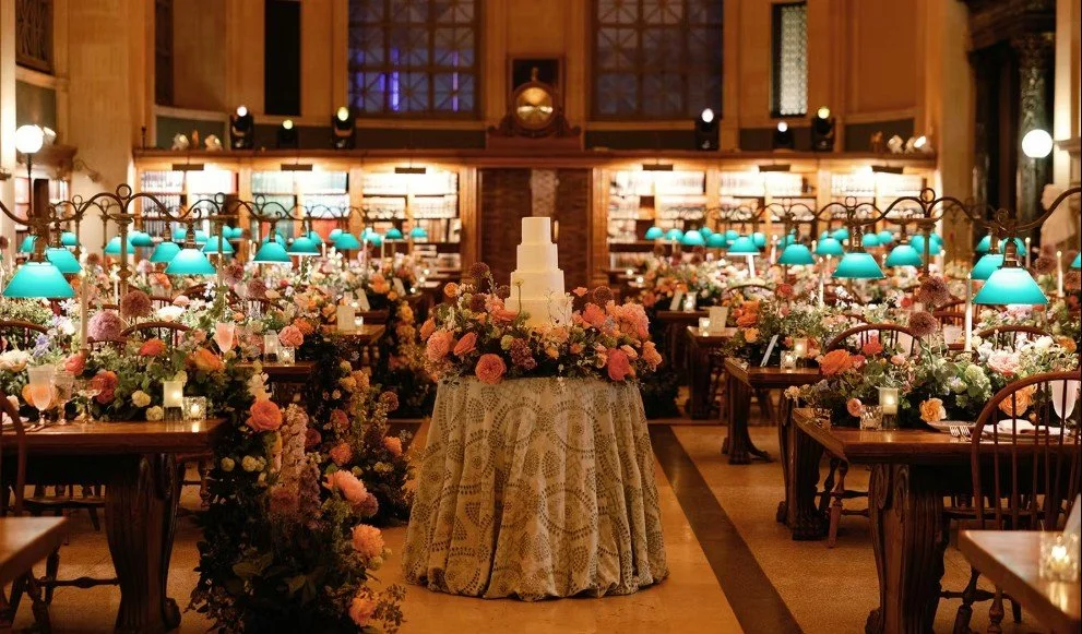 Wedding reception decorated with pastel-colored flowers and vintage furniture in a warmly lit, elegant room.