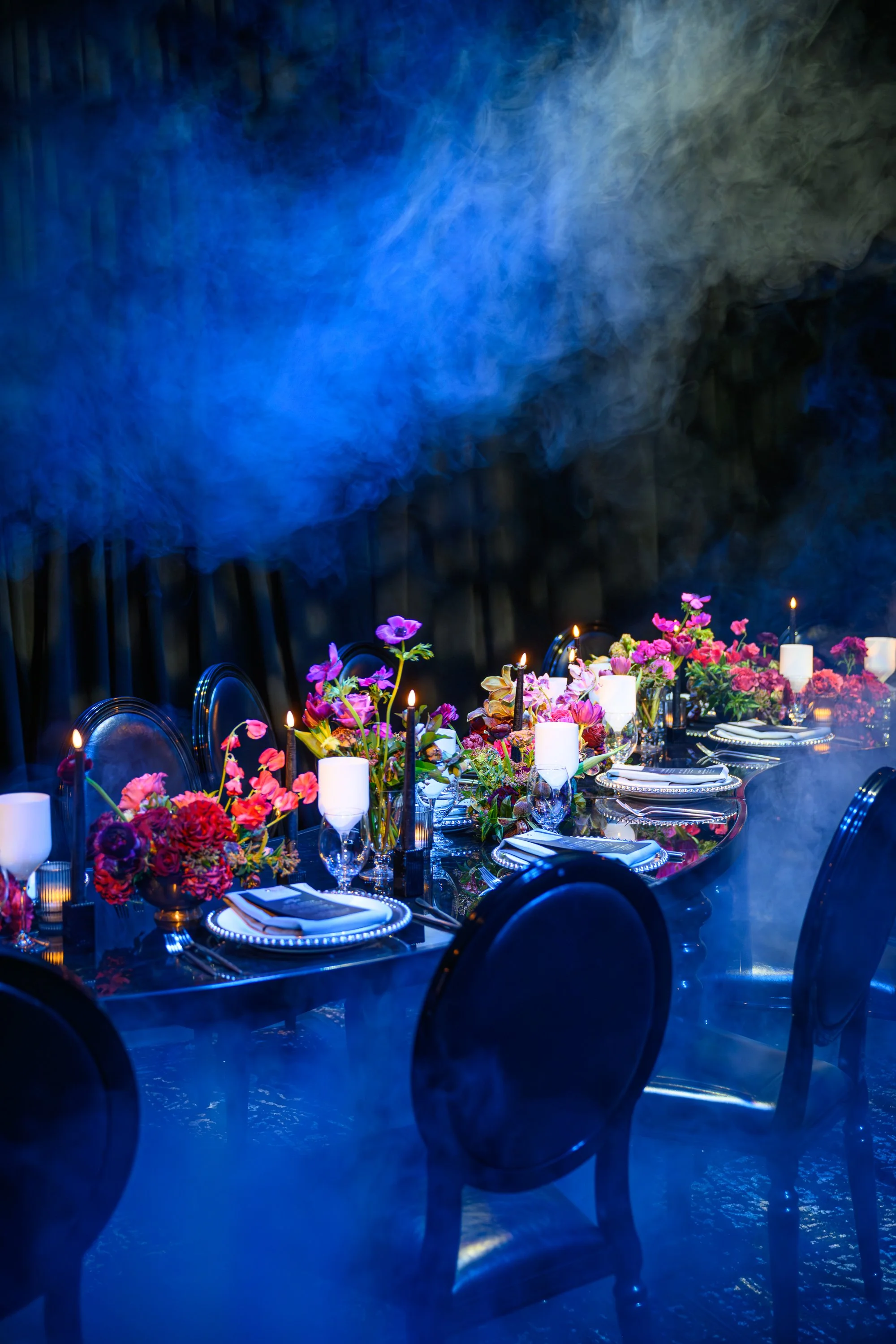 a table setting with a floral centerpiece, candles, and elegant tableware for a formal event