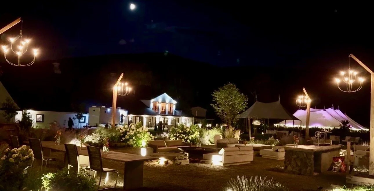 The moon over the farmhouse, the tent lit beyond the firepit garden