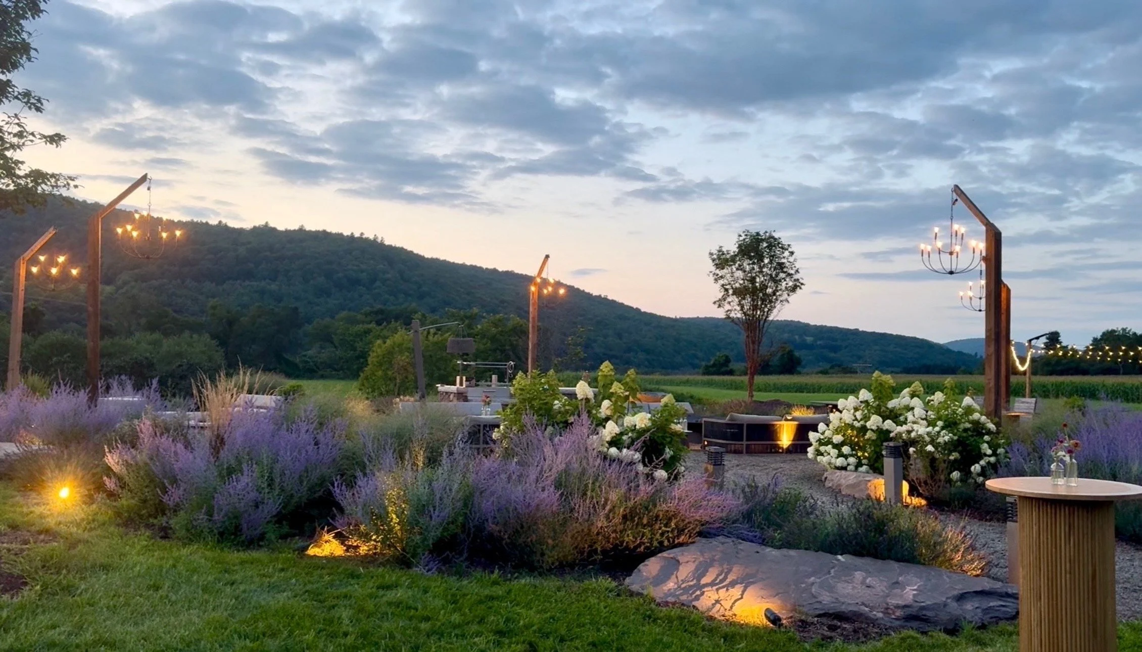 The firepit garden at dusk, chandeliers lit above the lavender