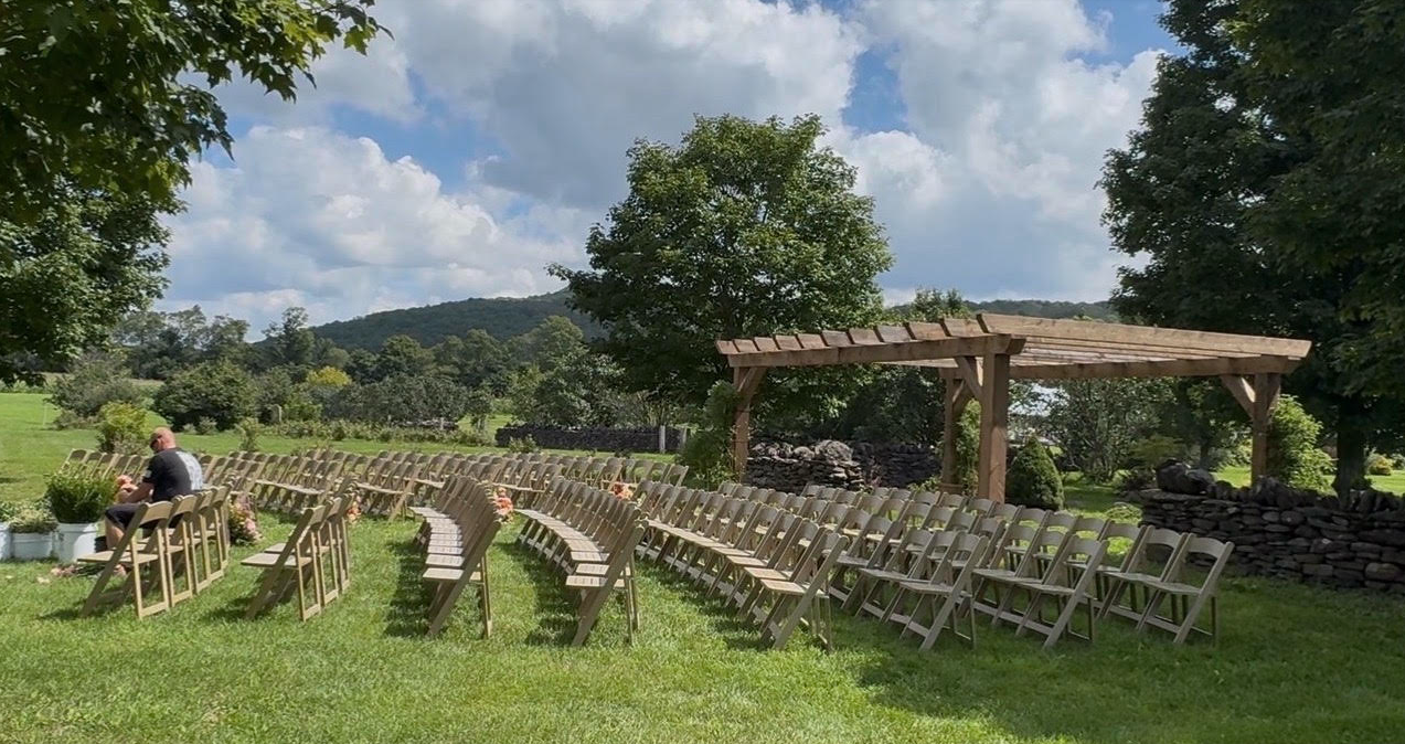 Rows of ceremony chairs facing the pergola, the hills beyond