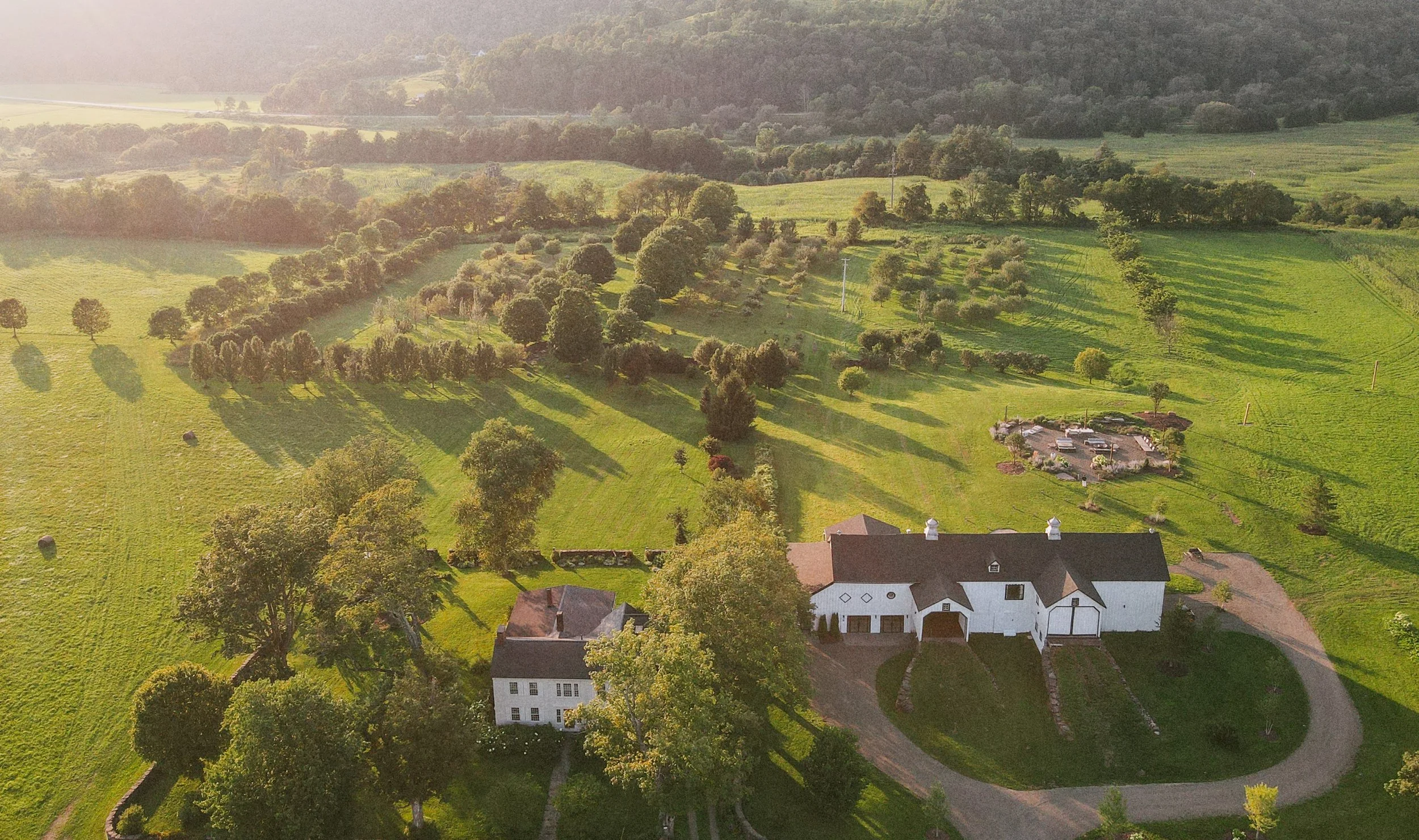 The farmstead, orchard, and valley from the air at golden hour