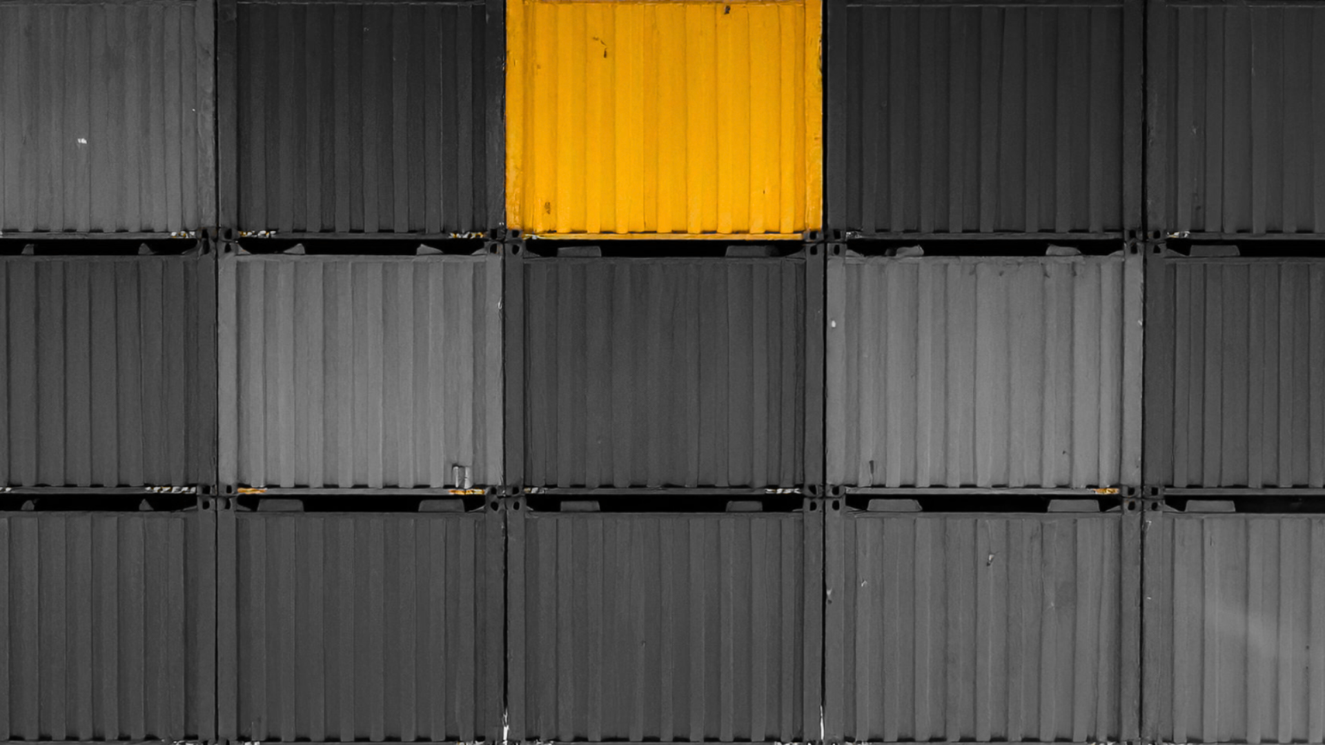 Stacked black storage containers with one yellow container in the top row, second column from the left.