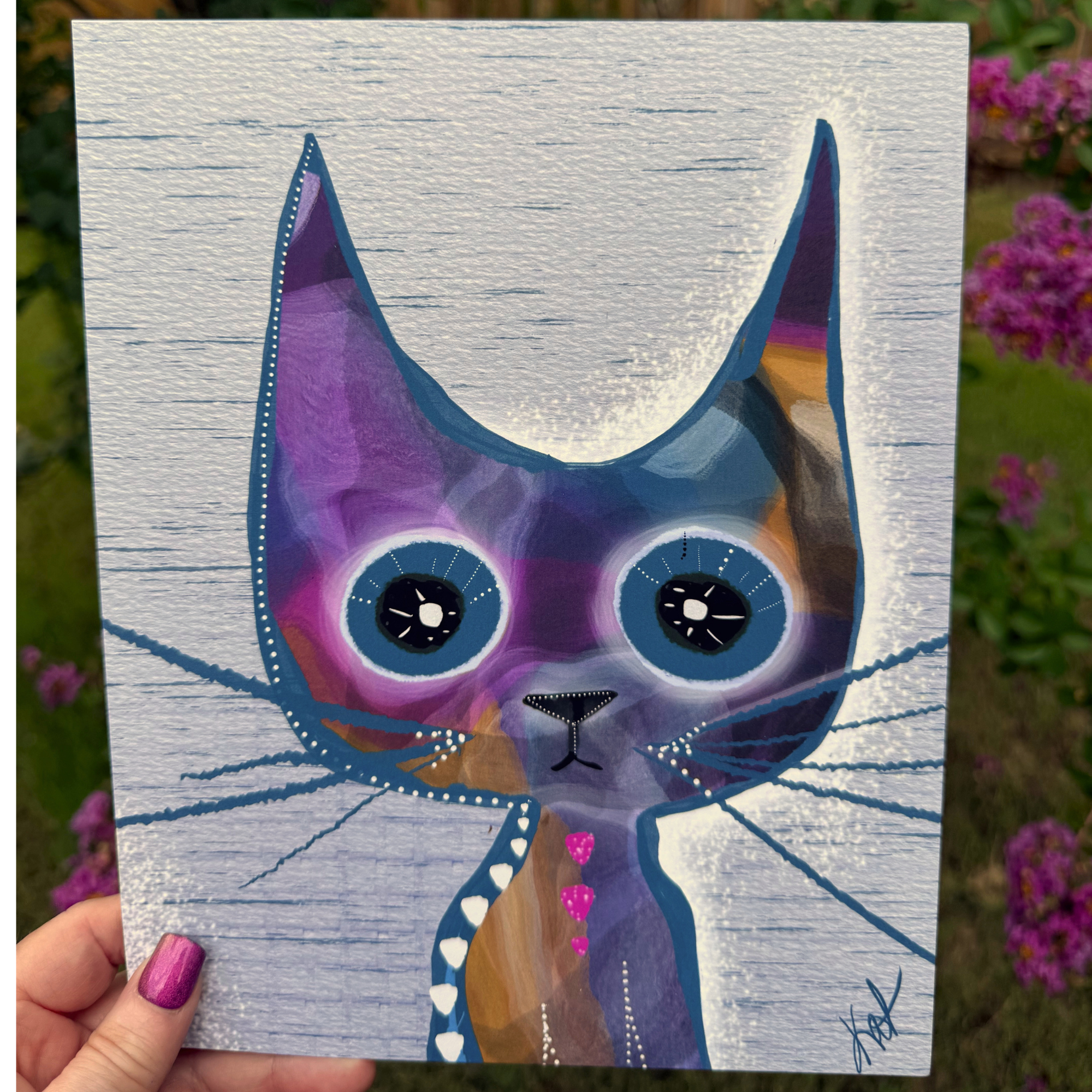 Paintbox Kitty whimsical cat art print by Wild Thorn Collective photographed outdoors among purple flowers.
