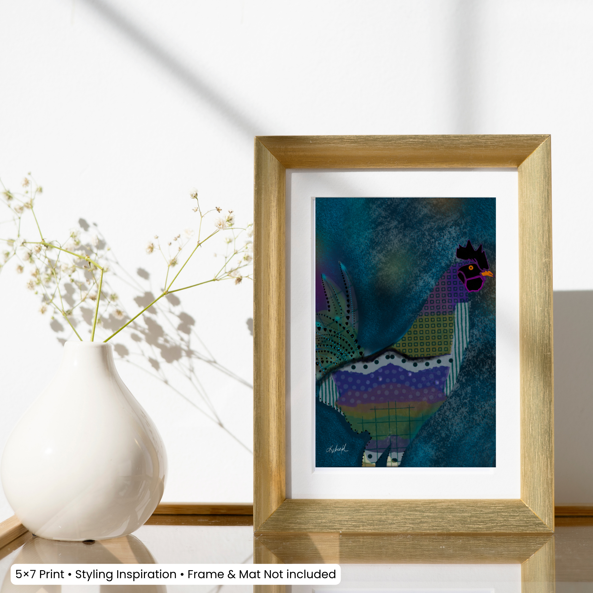 5x7 colorful rooster art print displayed matted in a gold frame on a tabletop beside a vase.