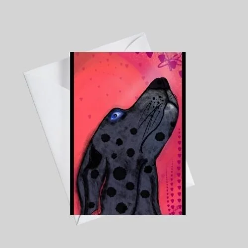 Whimsical black-and-gray dog greeting card gazing upward with a bright blue eye on a warm coral background with subtle heart details, shown with a white envelope, by Wild Thorn Collective.