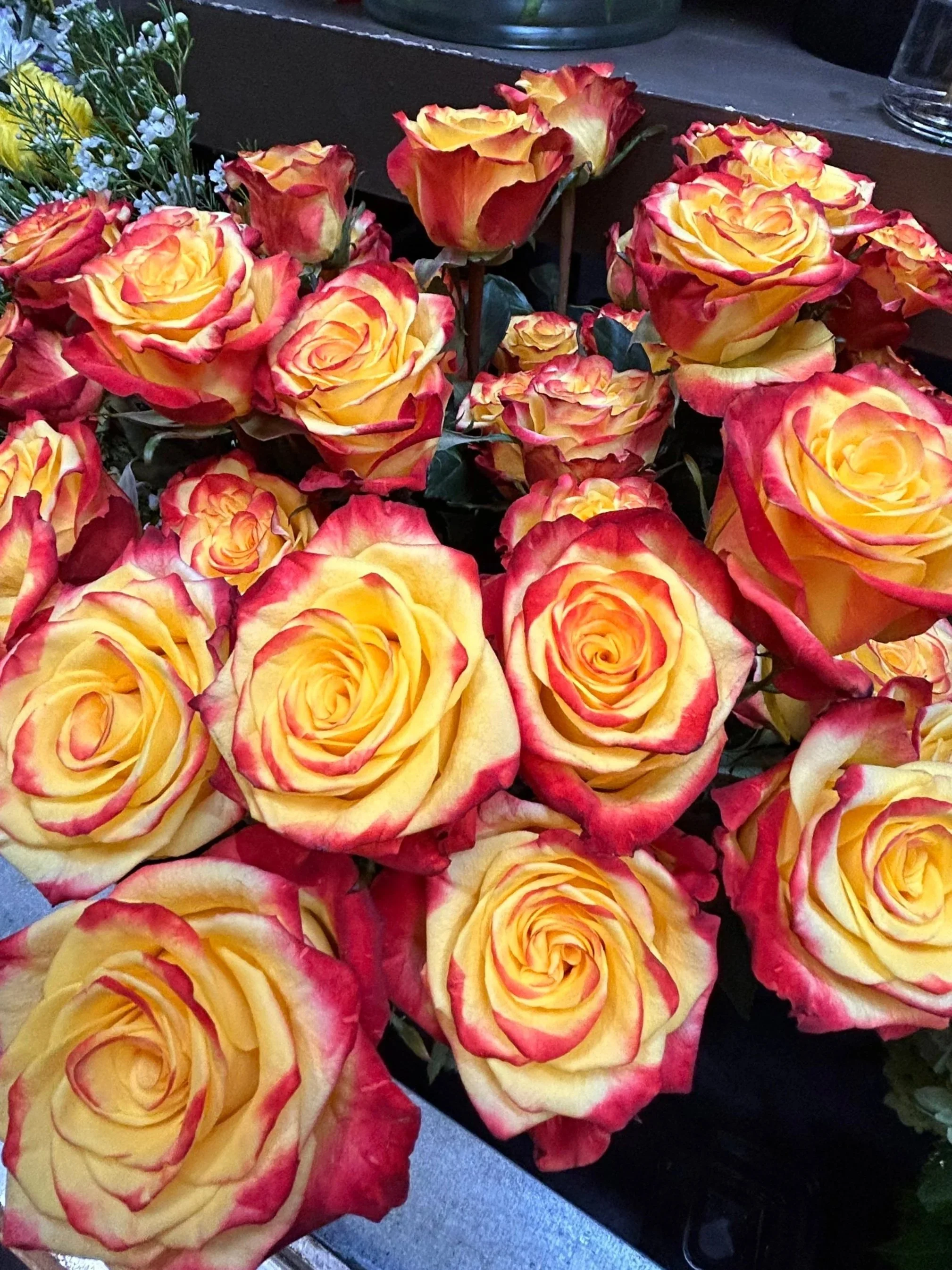 A close-up of bicolor yellow roses with red-tipped petals on display in a flower shop.