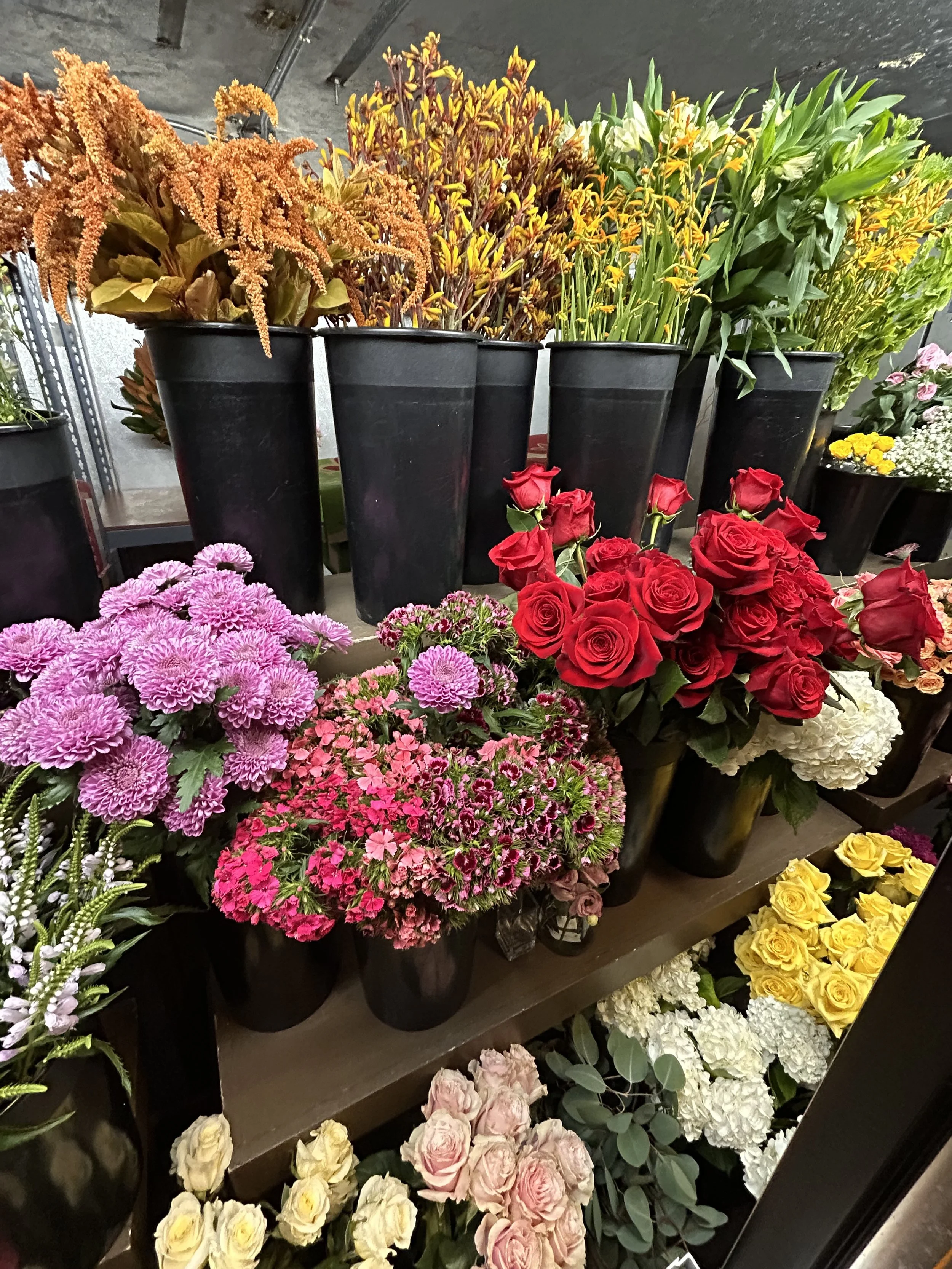 Various colorful flower arrangements in black vases on display in a flower shop.