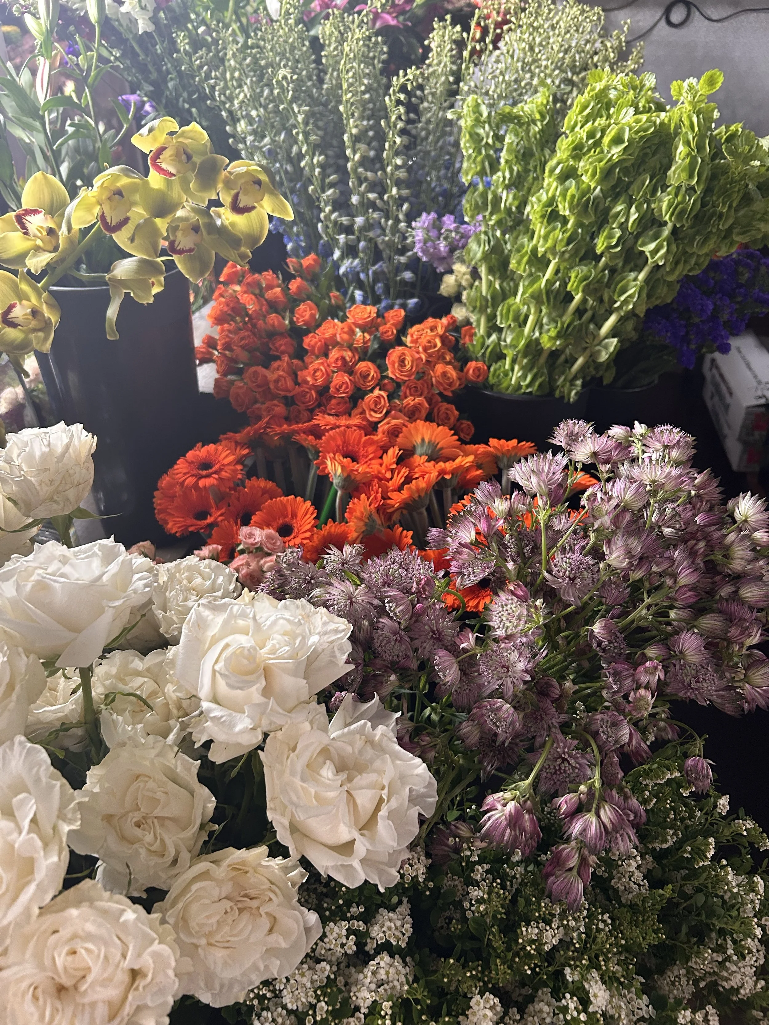 A colorful assortment of flowers including white roses, orange roses, and green hydrangeas in a display.