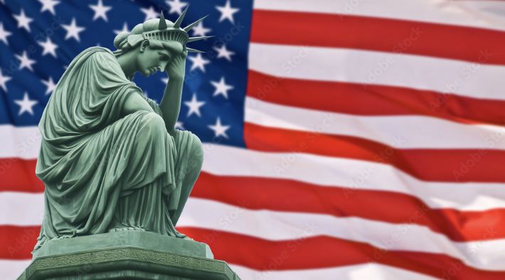 sad statue of liberty in front of american flag
