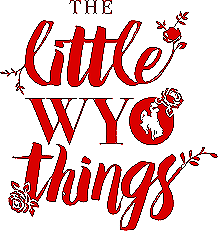 Artwork with the phrase "The Little W Wheel Things" in red, decorative lettering, featuring floral accents and a small globe bearing a silhouette of a cat.