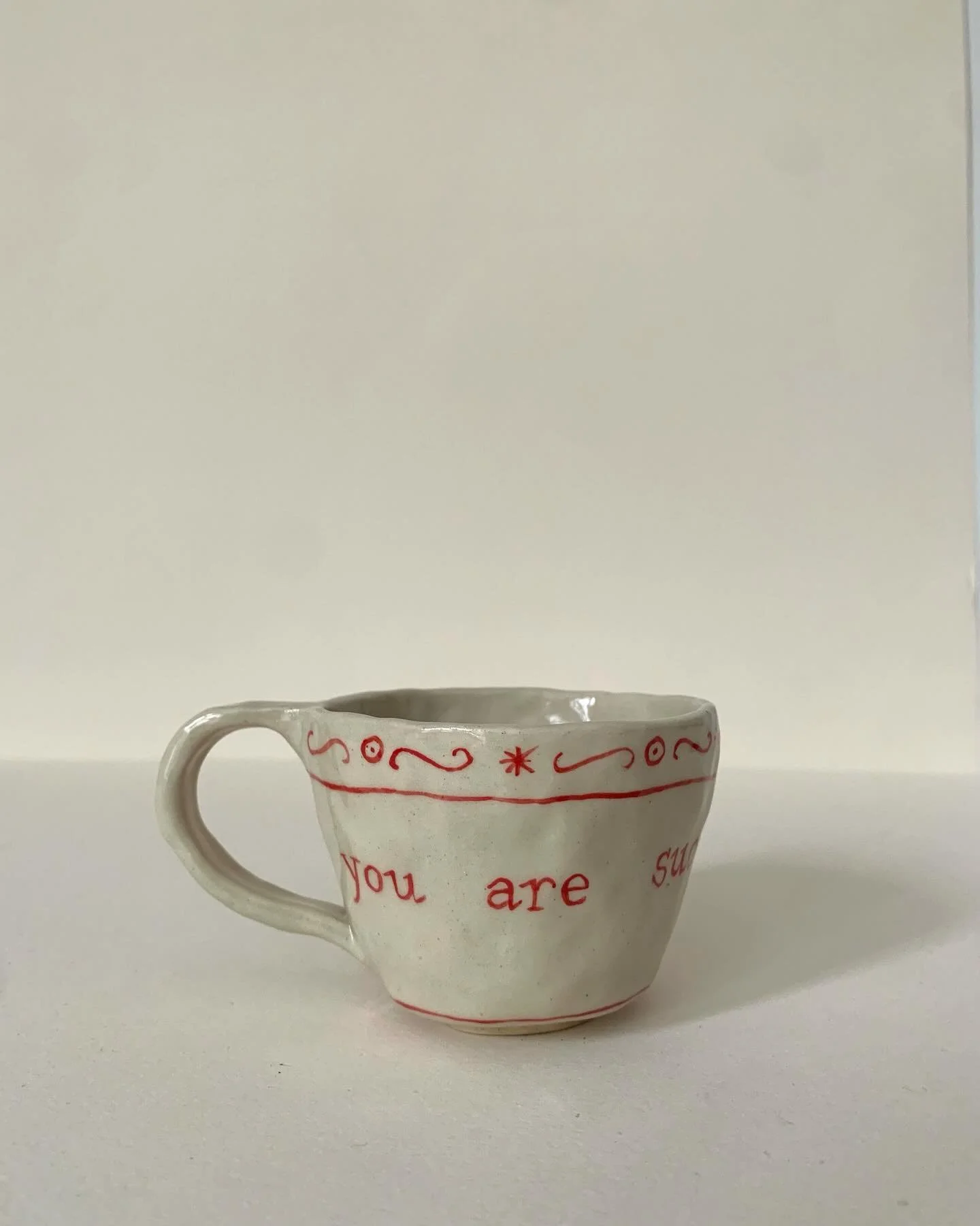 This little gem will be for sale this thursday at the @studio3tables sales. I&rsquo;ve been wanting to make a mug like this for a long time&hellip;

Image description: hand built pinched mug in off white stoneware, painted in red decorative flourishe