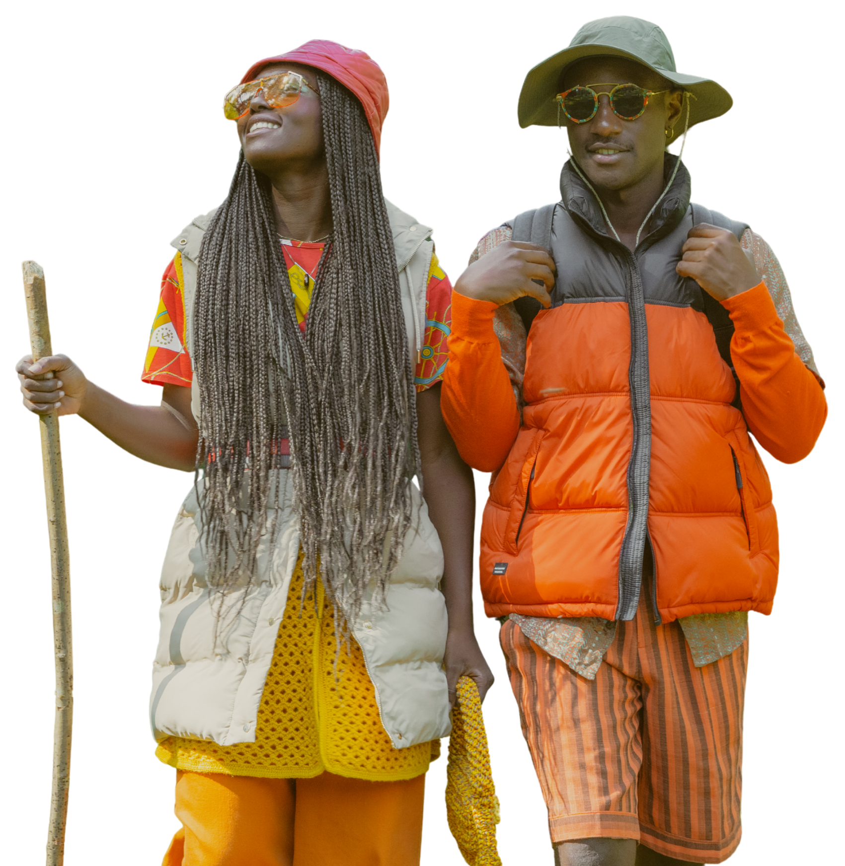 Two people dressed in colorful outdoor clothing standing outdoors, one holding a walking stick.