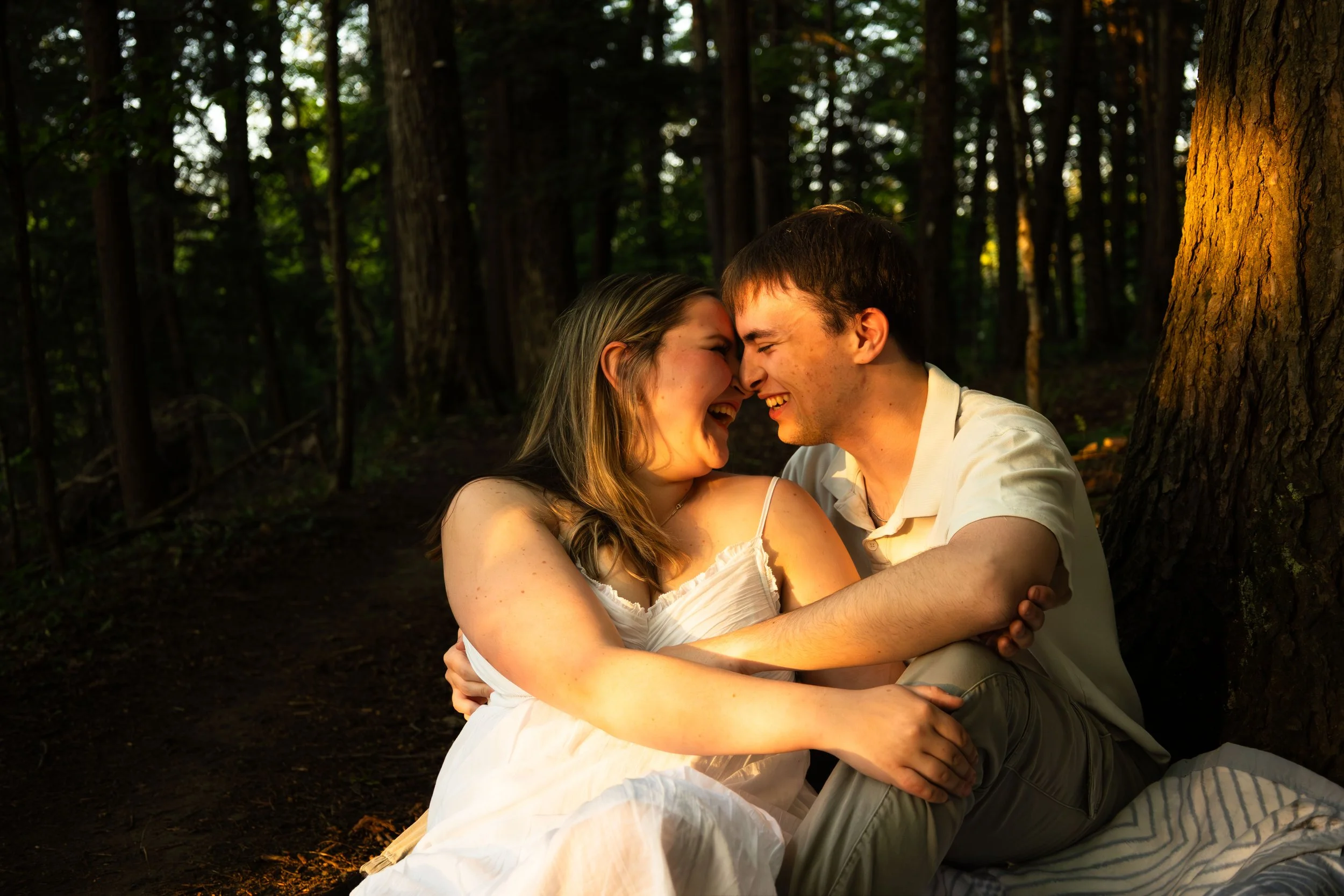 man and woman embracing on the ground, heads tilted towards each other in laughter