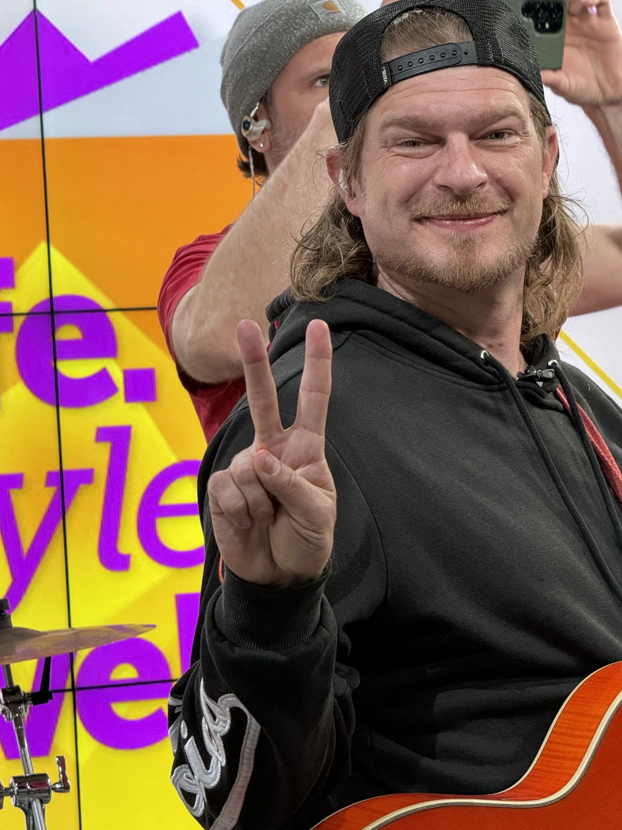 Russ Baum smiling, making peace sign, on set at Life Style Live Indy.