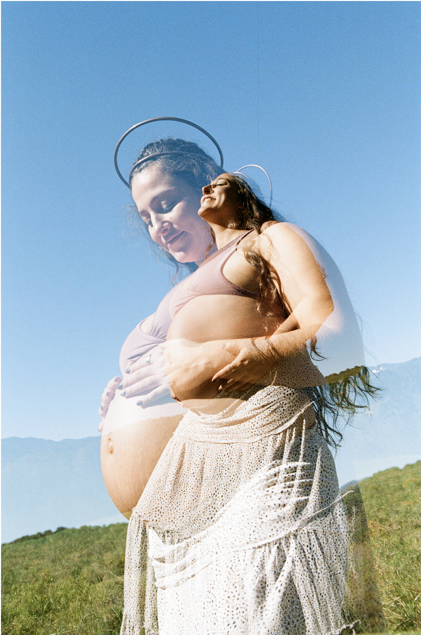 Double exposure of a pregnant woman smiling outdoors, with a faint overlay of her face, against a bright blue sky and green grass.
