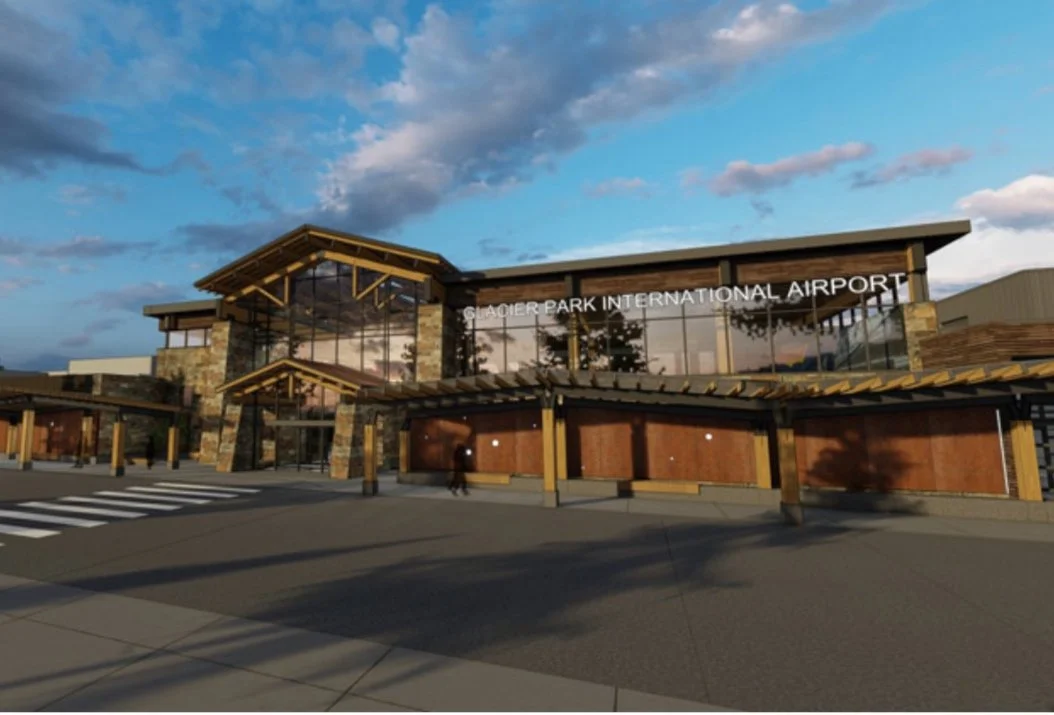 Gerald R. Ford International Airport terminal building with glass windows and stone accents, under a partly cloudy sky.