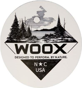A black and white design with trees, a lake, and clouds, featuring the text 'WOXX' and 'Designed to Perform. By Nature.' and 'N° USA' at the bottom.