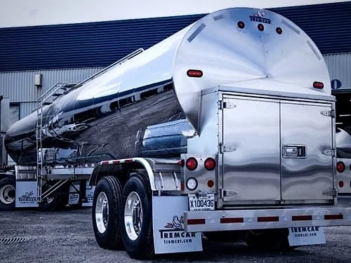 Stainless steel tanker trailer parked at an industrial facility.