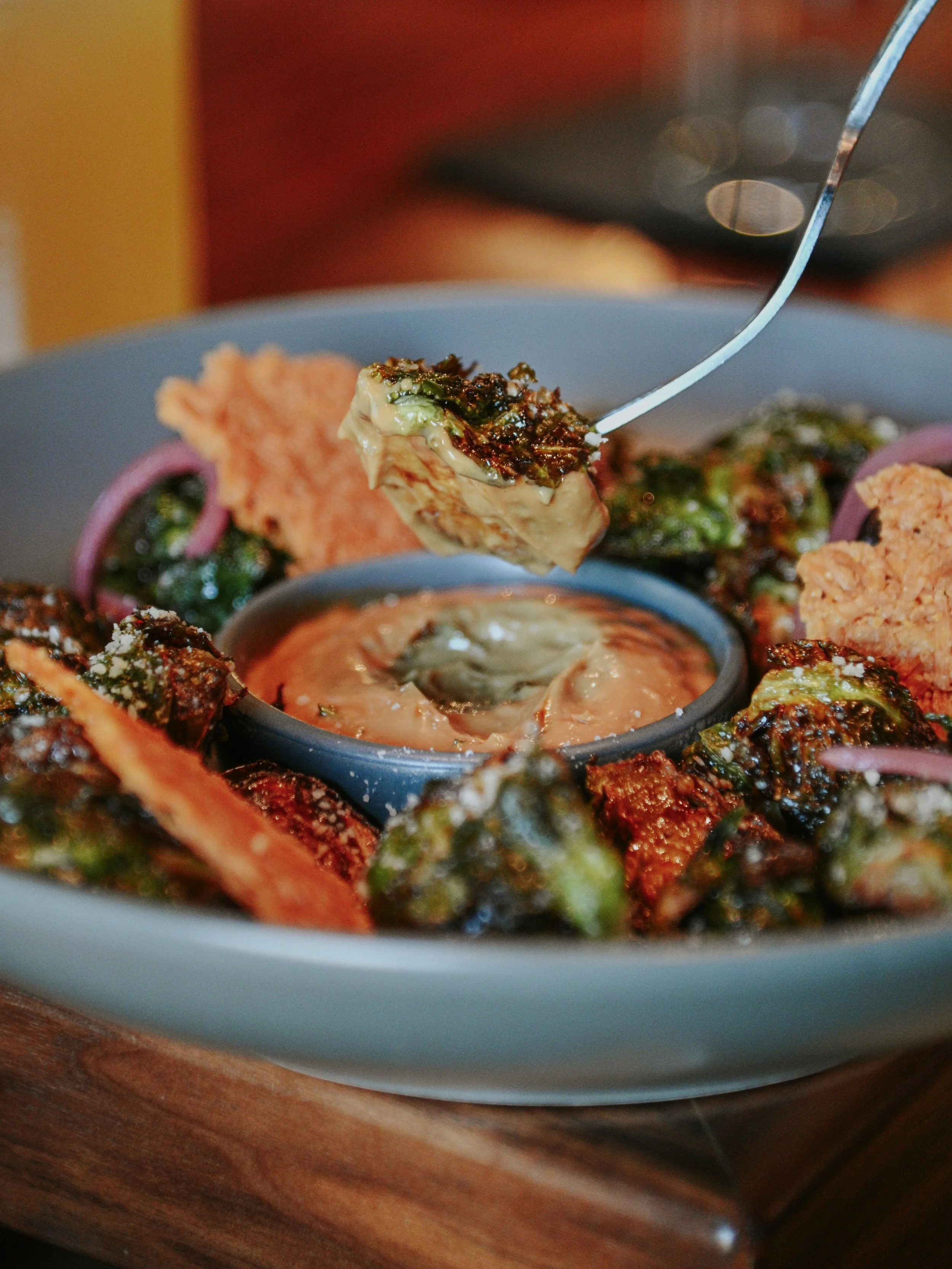 Close-up of a plate of Indian street food with a fried snack, vegetables, and a small container of dipping sauce.
