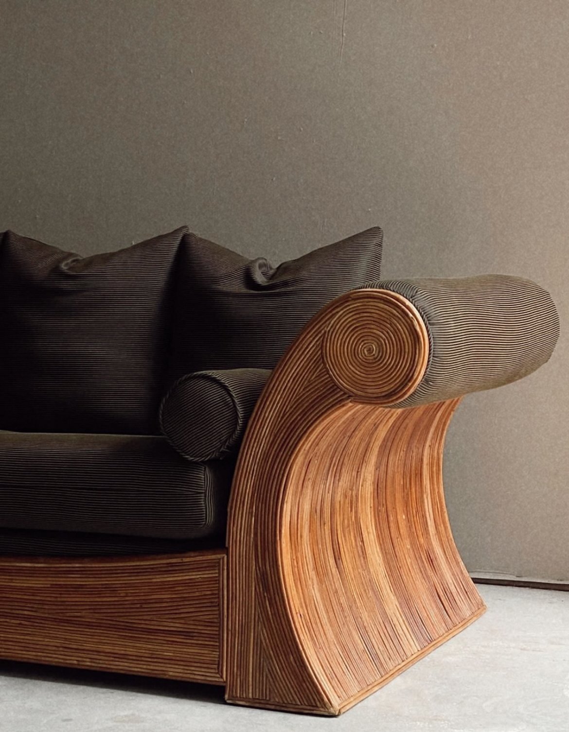 Close-up of a sofa with dark velvet fabric and unique wooden armrest design.