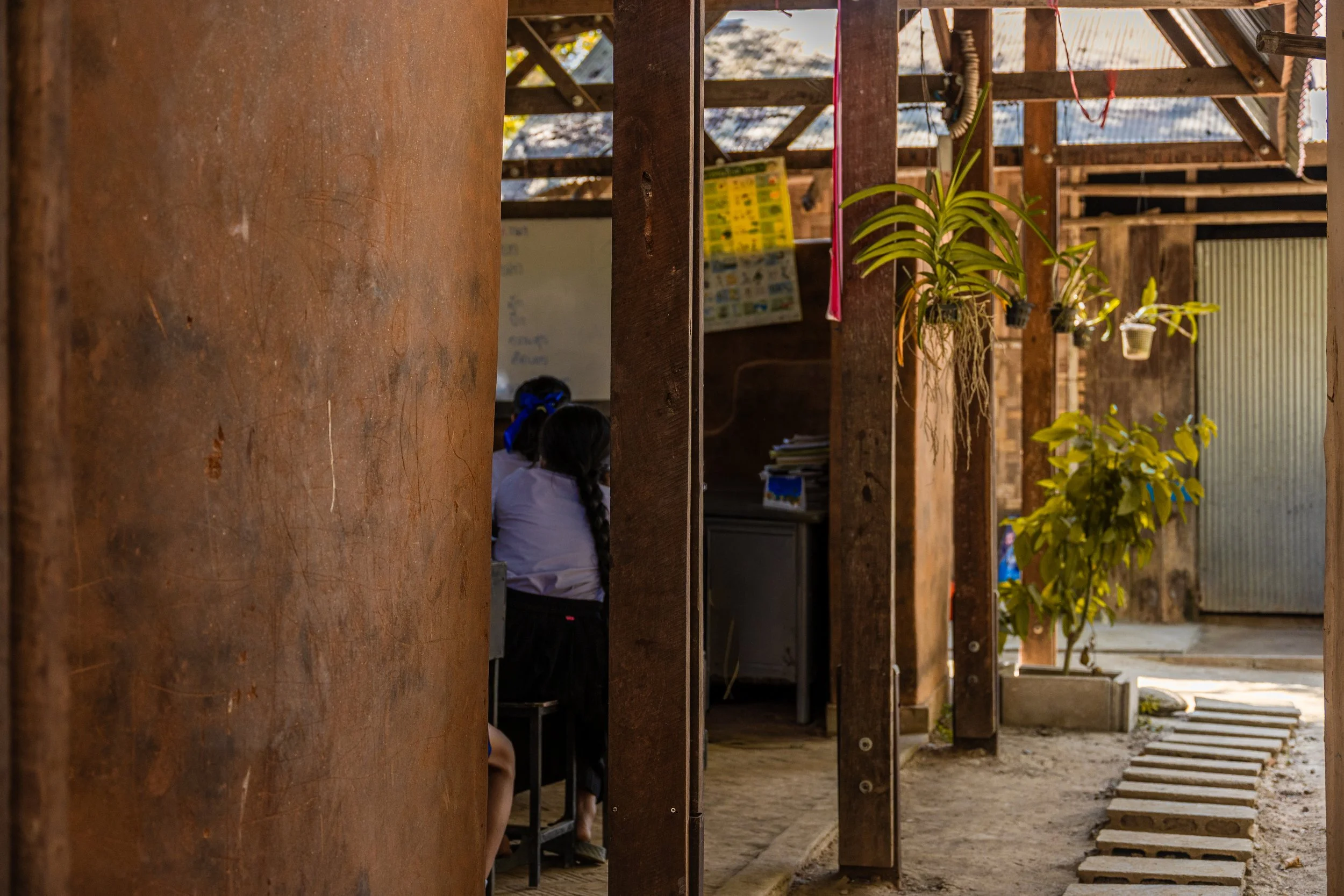 two kids inside a bamboo building looking through a window